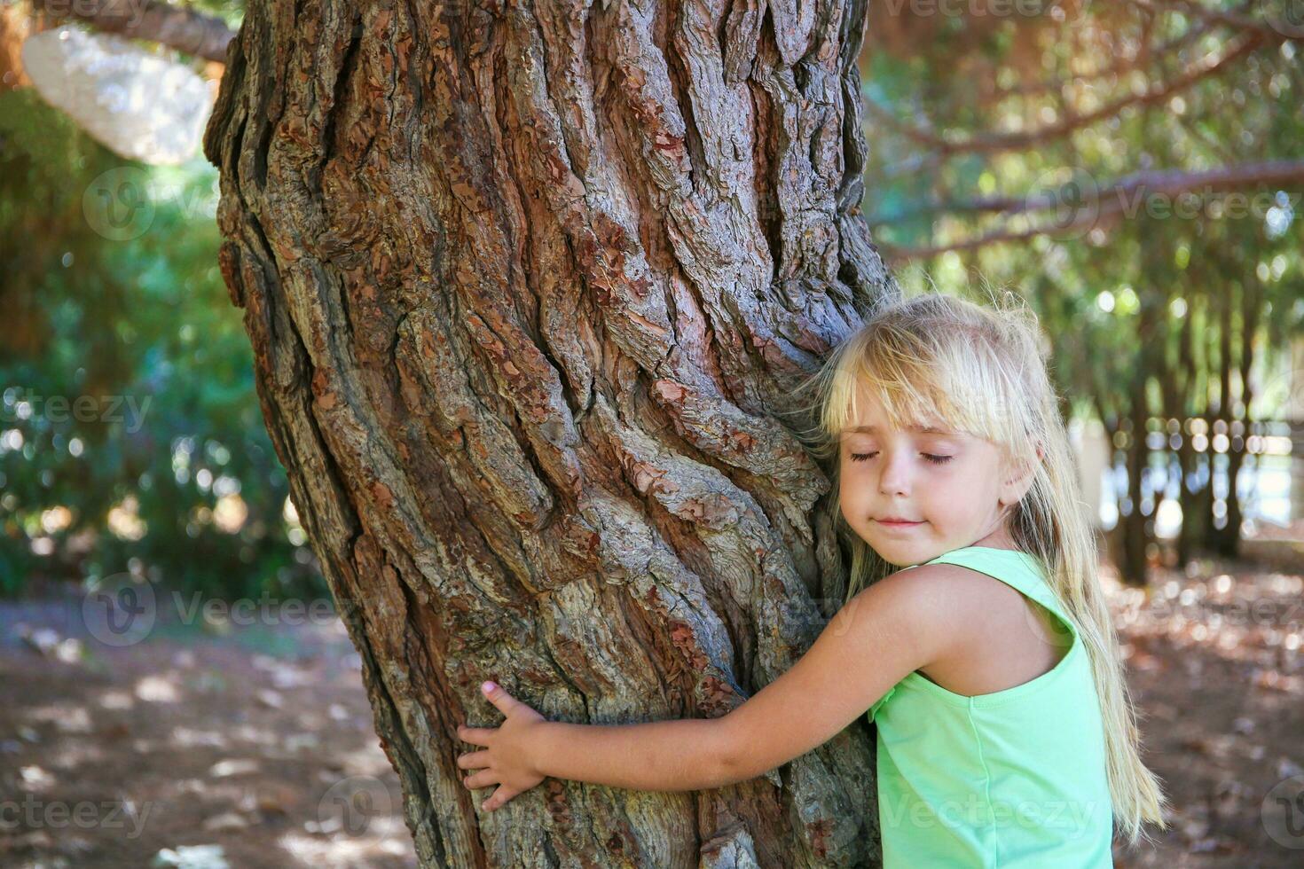 Girl hugging tree in park. photo