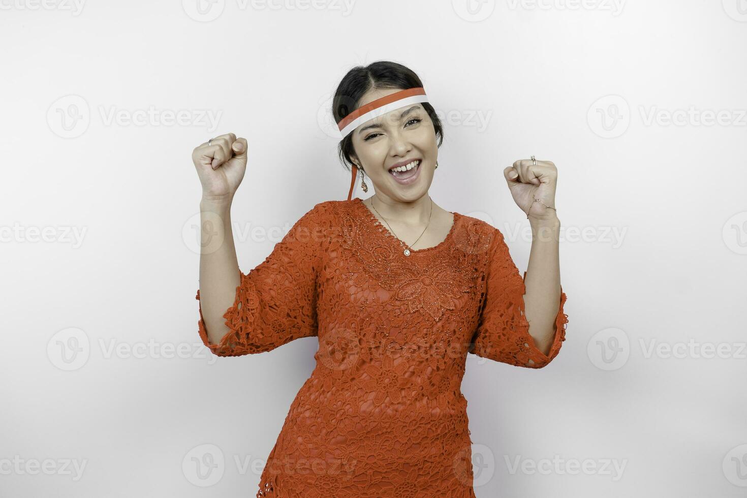 A young Asian woman with a happy successful expression wearing red kebaya and headband isolated by white background. Indonesia's independence day concept. photo