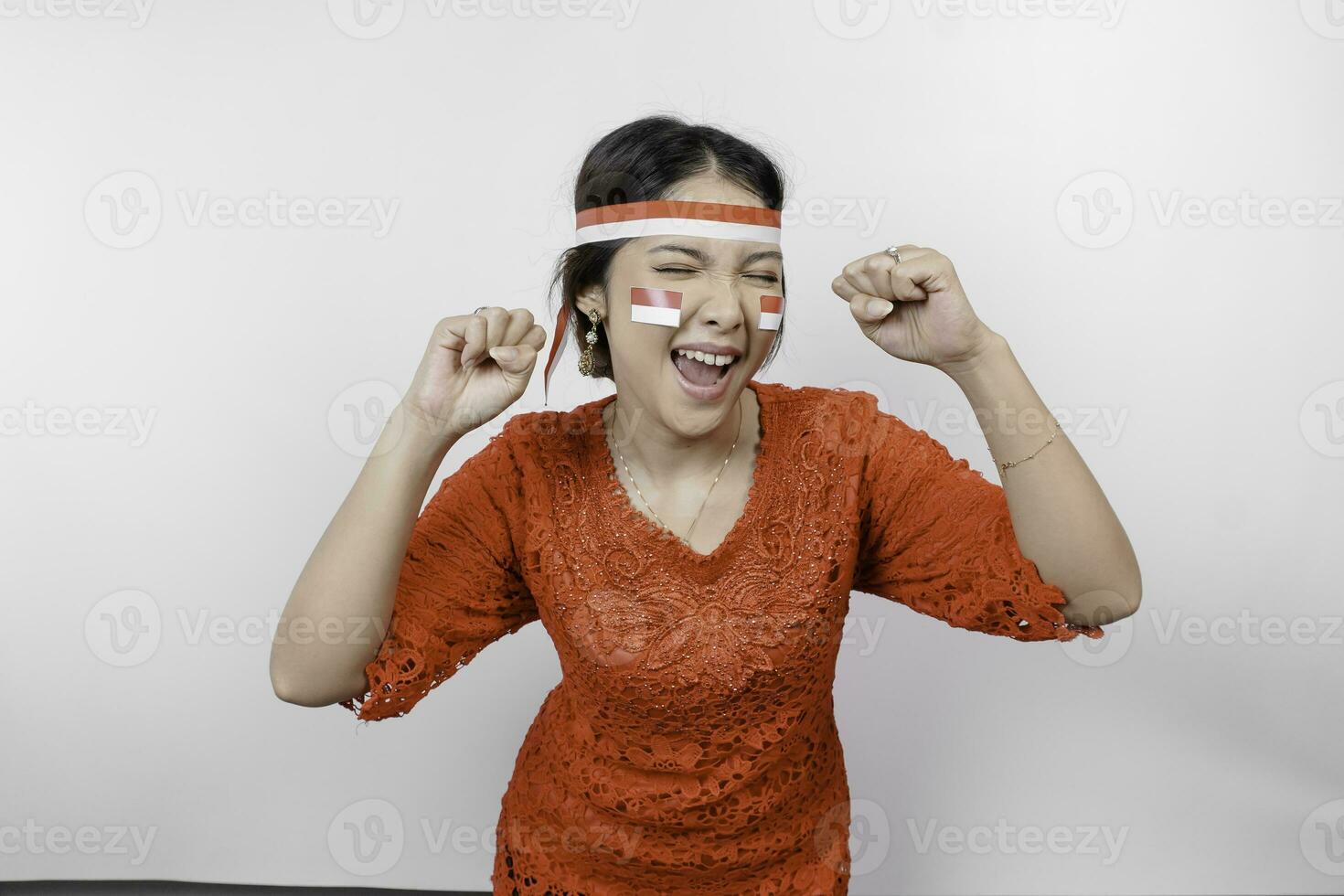 A young Asian woman with a happy successful expression wearing red kebaya and headband isolated by white background. Indonesia's independence day concept. photo