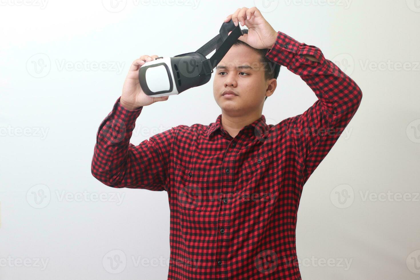 Portrait of Asian man in red plaid shirt getting ready and using Virtual Reality VR. Isolated image with copy space on white background photo