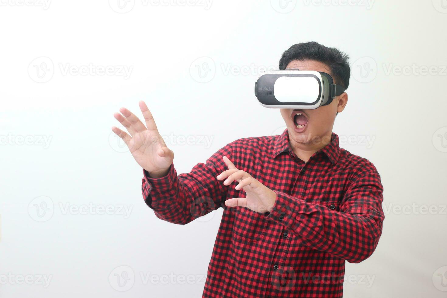 retrato de asiático hombre en rojo tartán camisa utilizando virtual realidad vr lentes y proteger él mismo por extensión su brazos desde alguna cosa grande que cae desde arriba. aislado imagen en blanco antecedentes foto