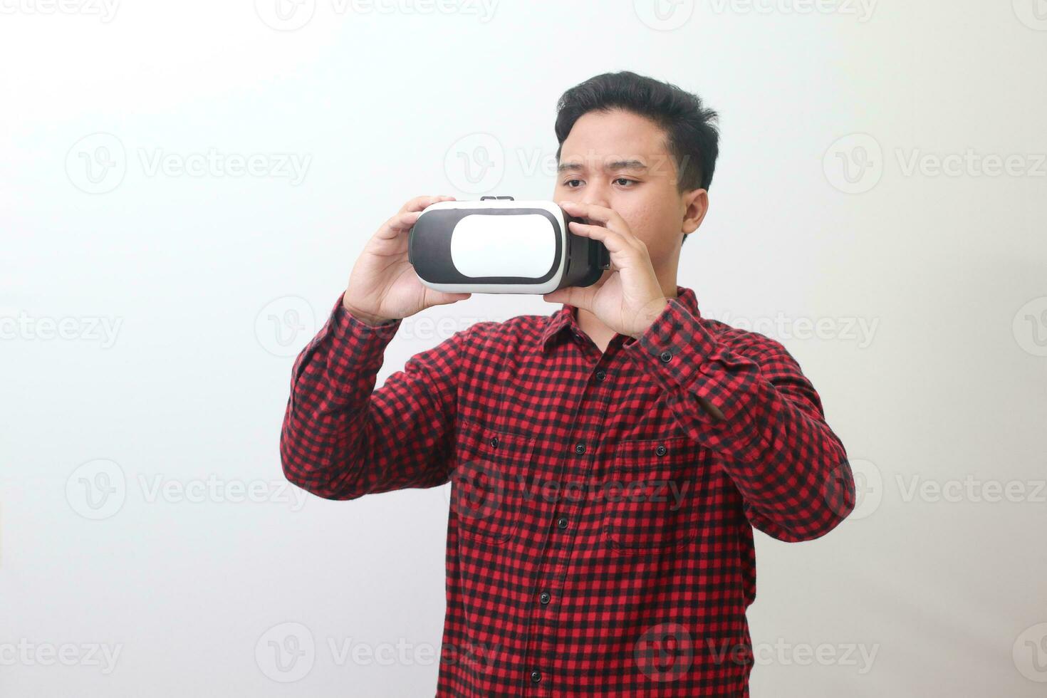 Portrait of Asian man in red plaid shirt getting ready and using Virtual Reality VR. Isolated image with copy space on white background photo