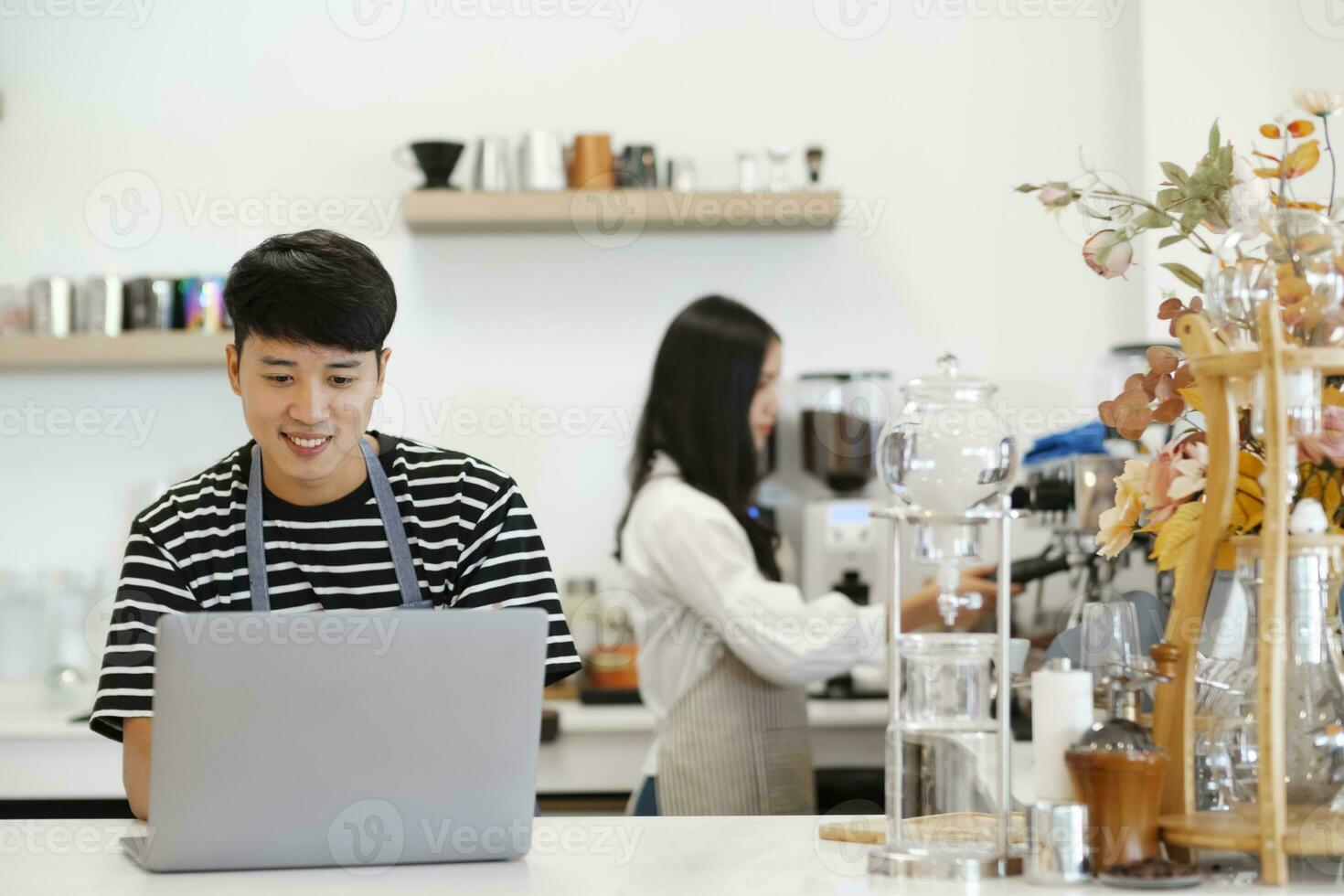 Two young managers or shop owners having some discussion working on a laptop at the counter of the shop or cafe. photo