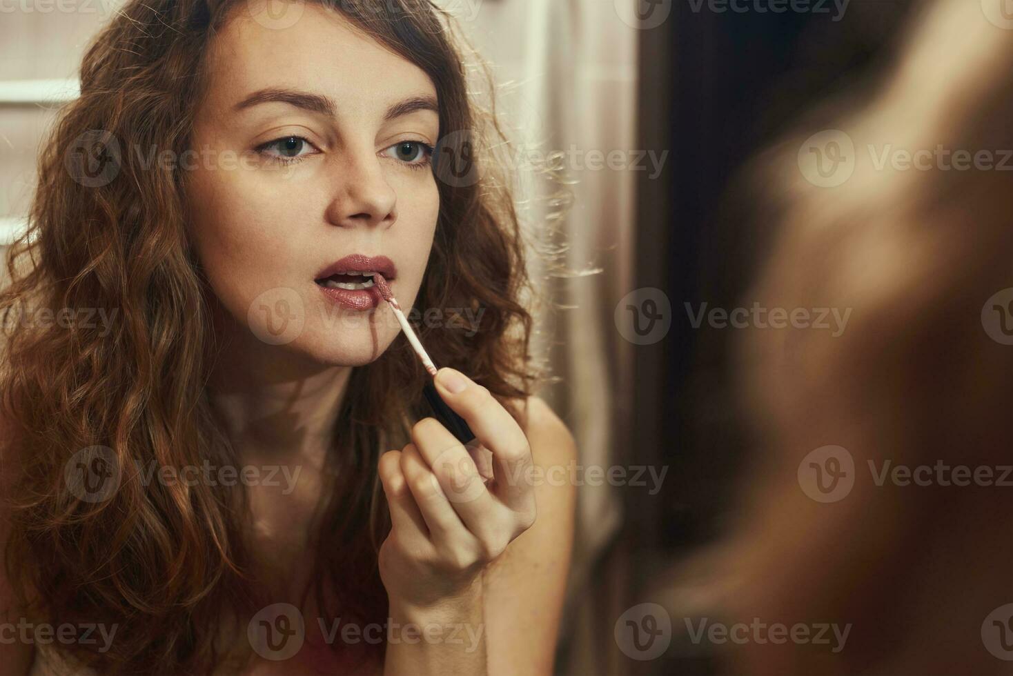 Woman applying make up in front of mirror photo