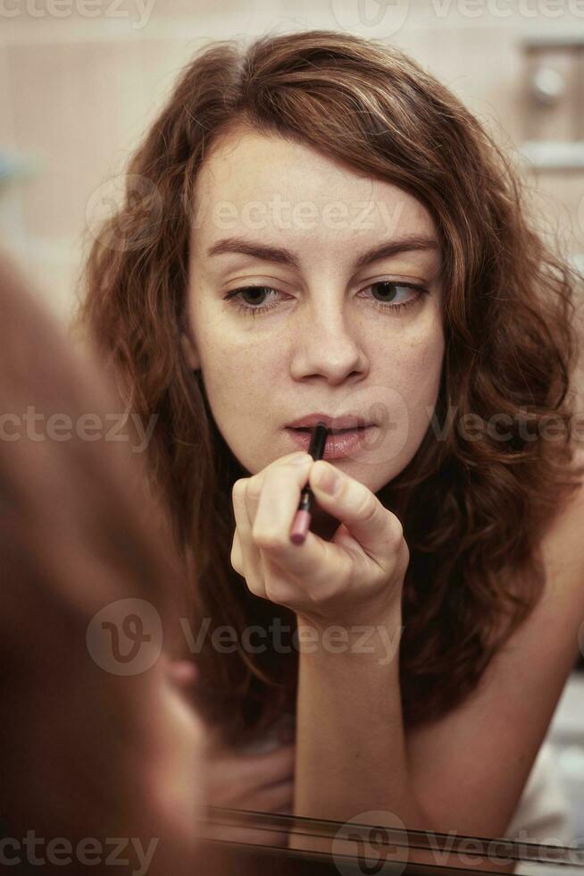 Woman applying make up in front of mirror photo