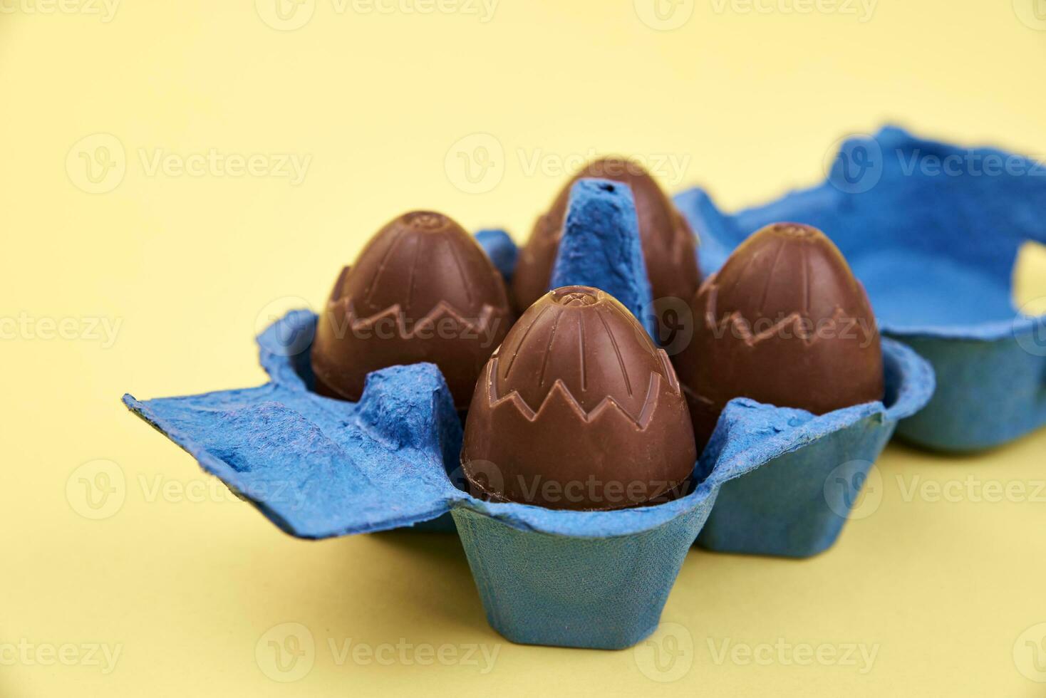 Chocolate eggs in box holder on yellow background photo