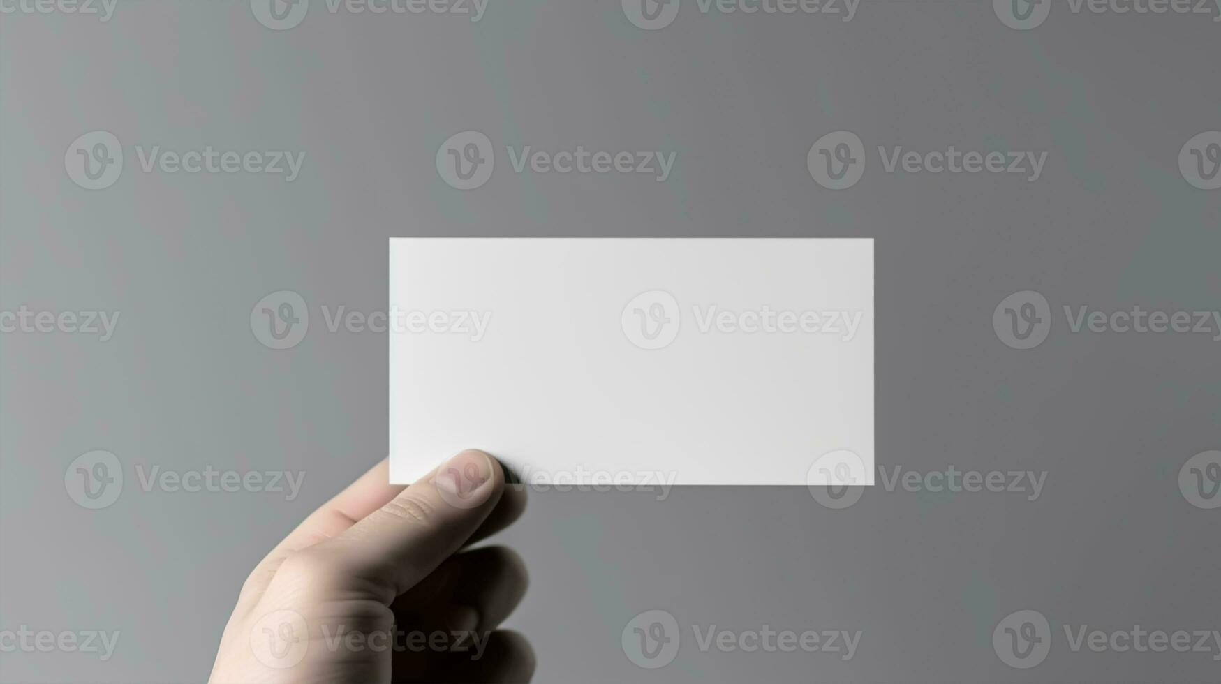 Hand holding a blank business card on a gray background, close up mockup photo