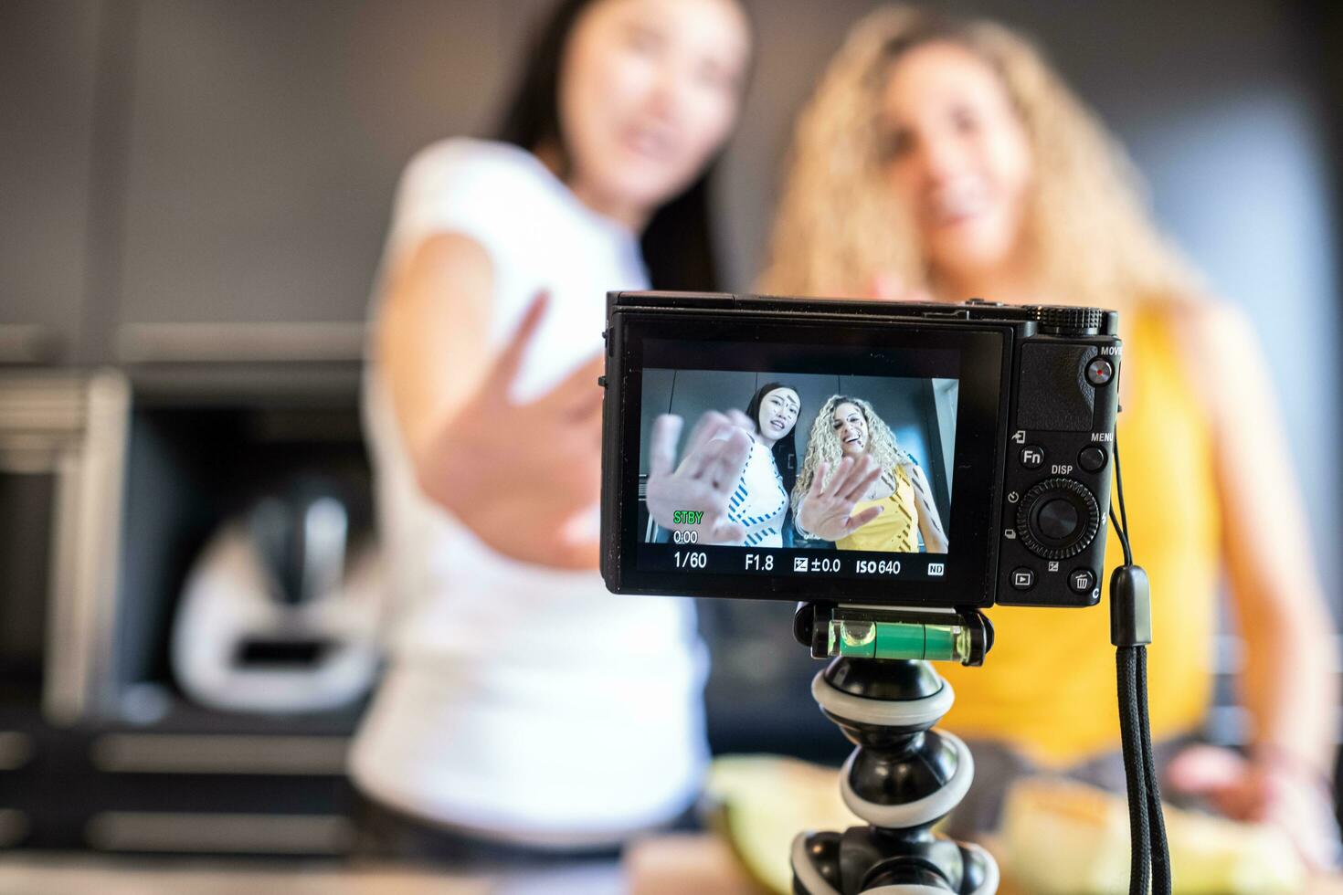 chinese girl and white girl shooting a video in the kitchen for blog photo