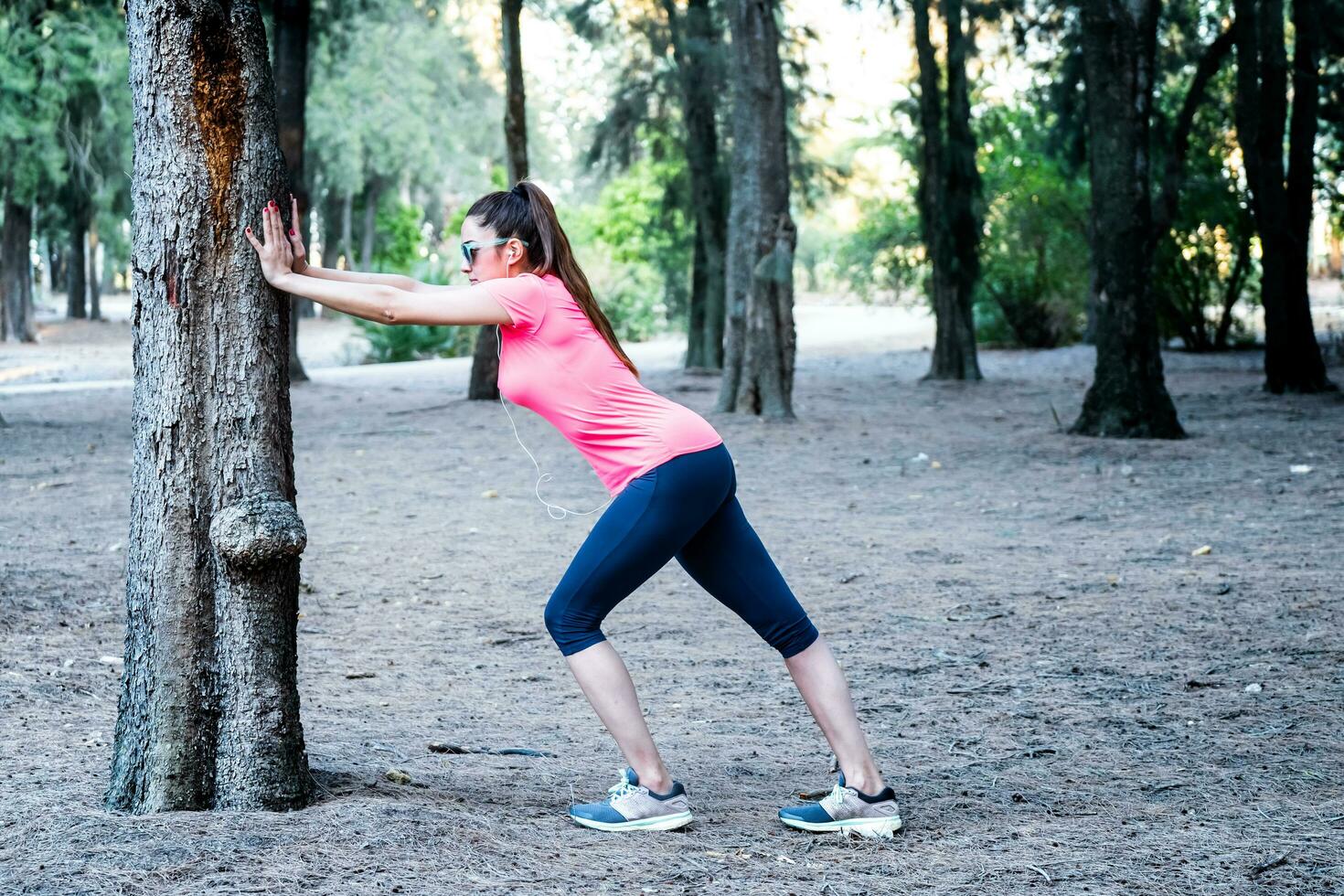 white woman stretching over a tree in a park photo