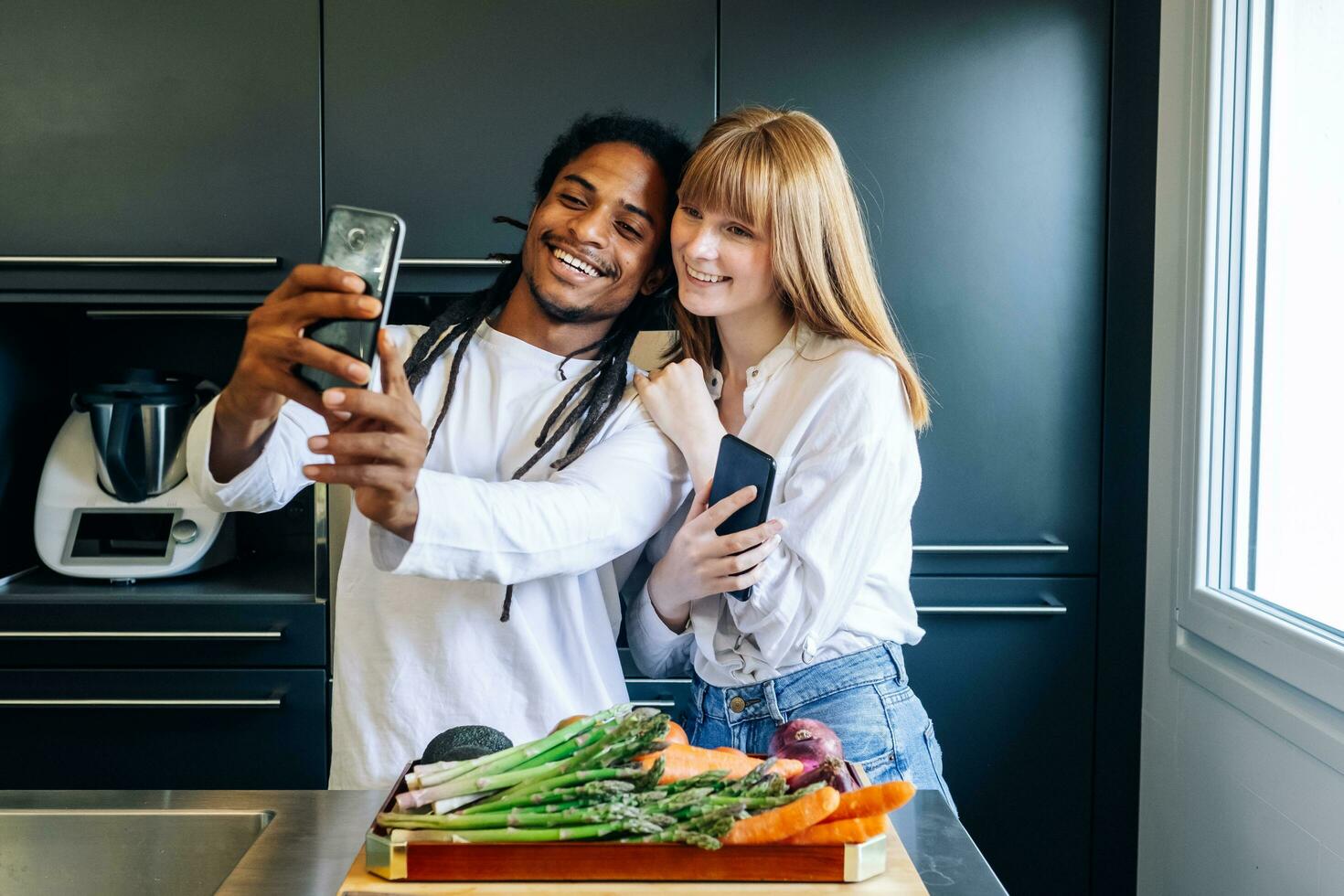 african american boy and white girl making a selfie in the kitchen photo