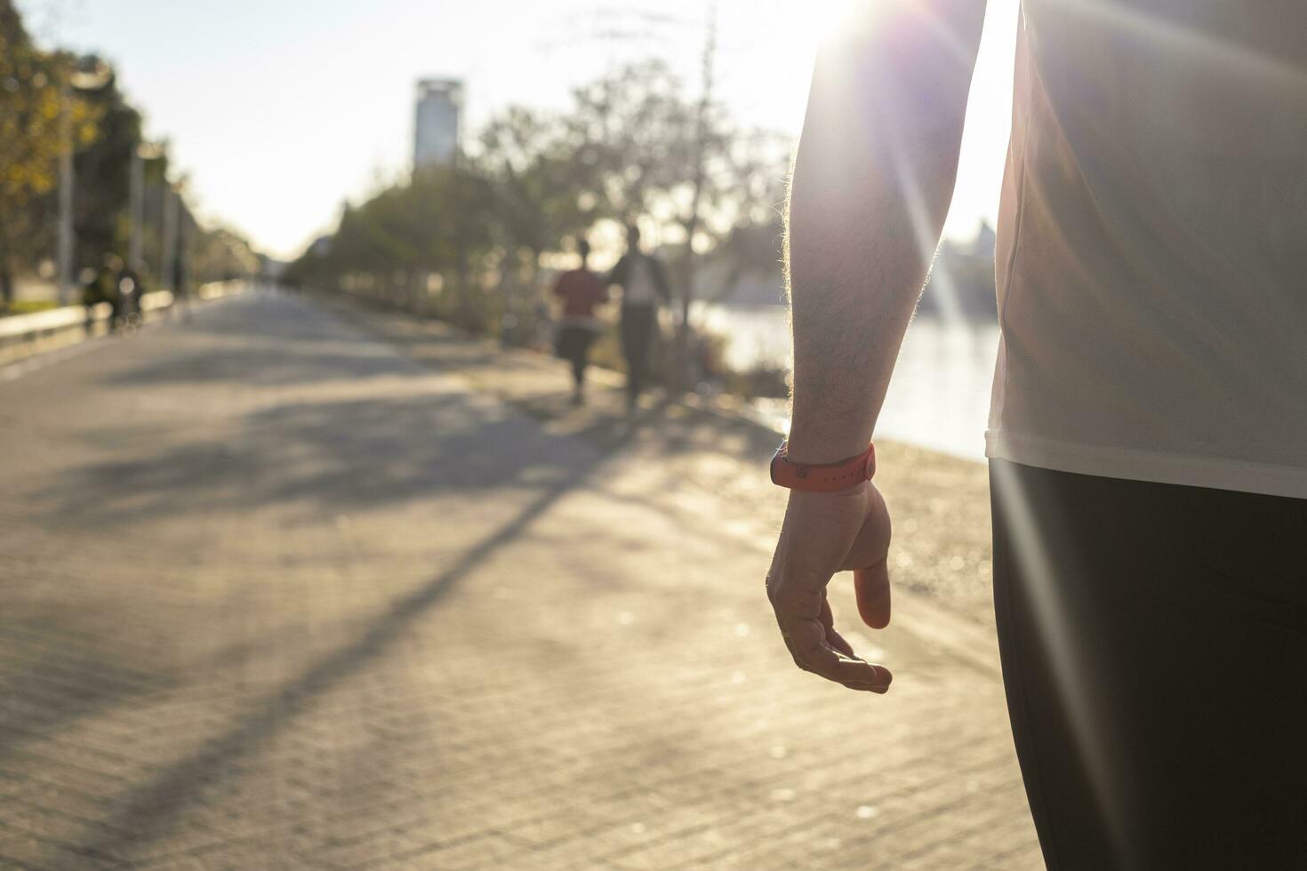 A closeup shot of a red watch on a male hand walking in the street on a sunny day photo