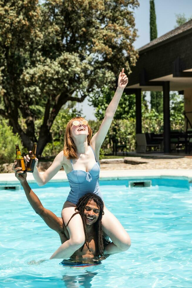 African-American man and white woman playing in a pool. photo
