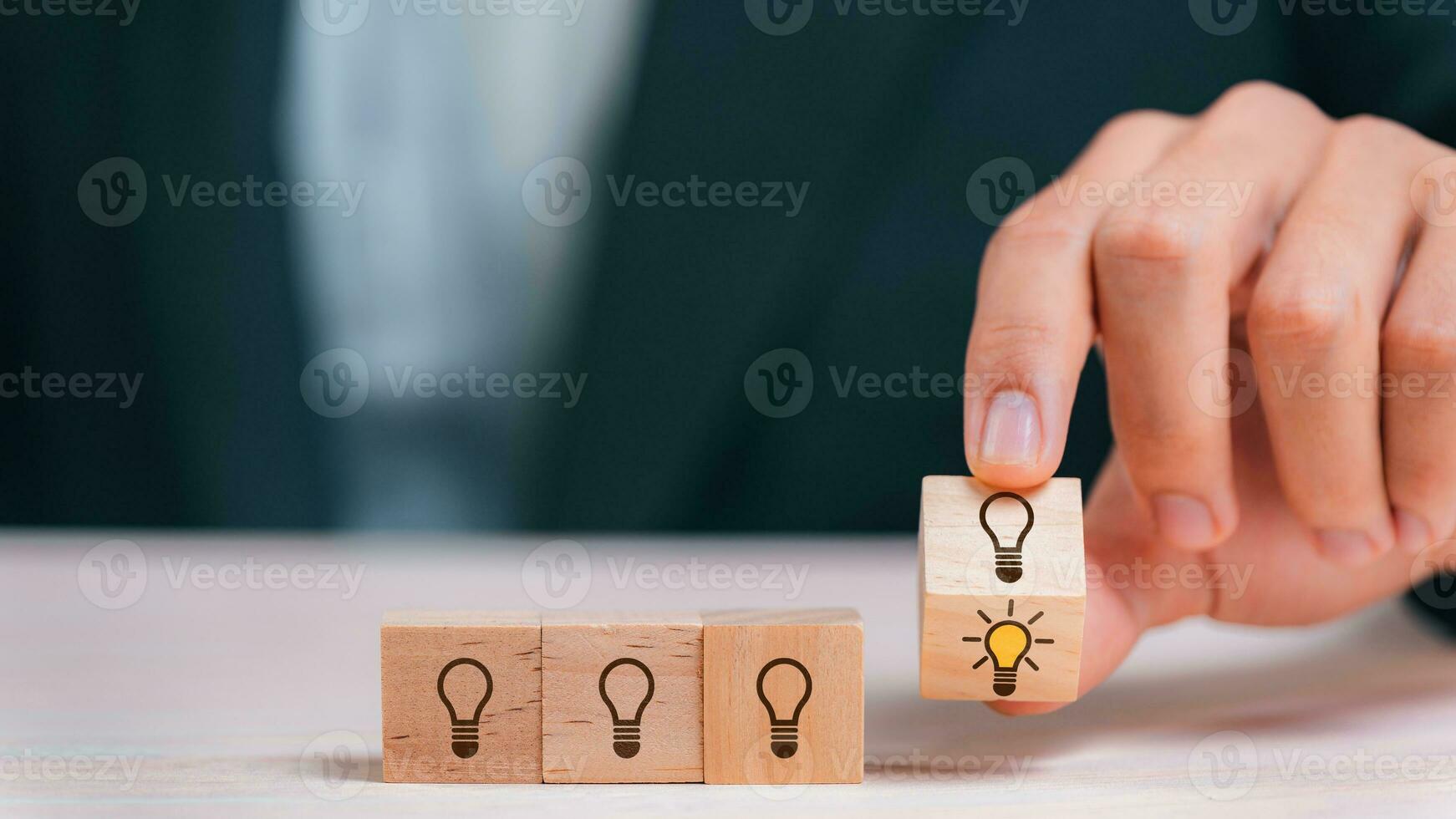 Leader choosing the best new idea with light bulb icon on wooden blocks. Explore creative design, solutions, strategy reviews. Inspiring innovation and teamwork. photo
