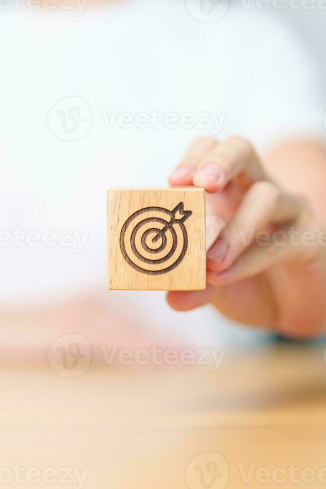 hand hold dartboard block with business goal, strategy, target, mission, action, objective, aim and success concept photo