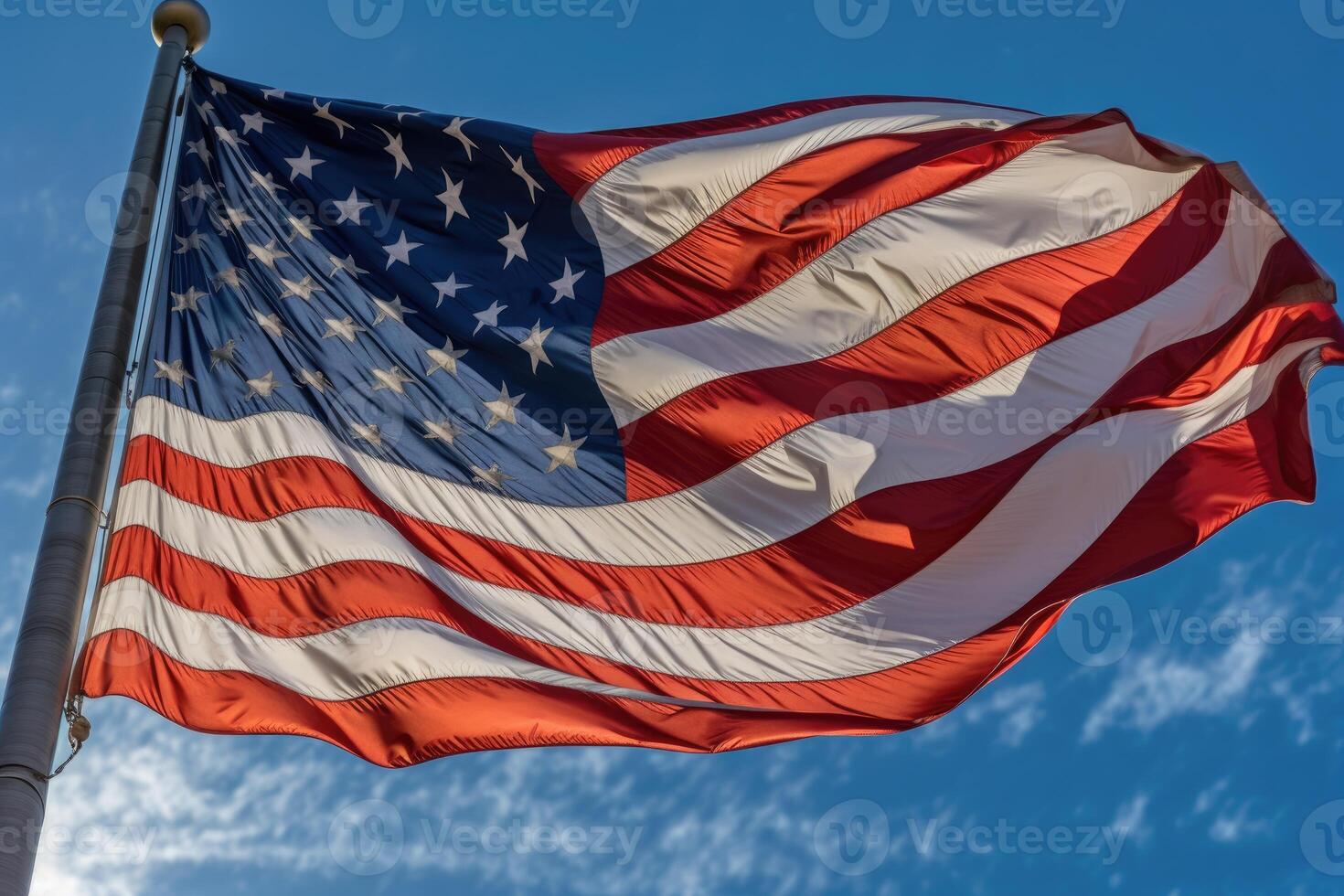 A powerful image of an American flag waving proudly in the wind against a clear blue sky. photo
