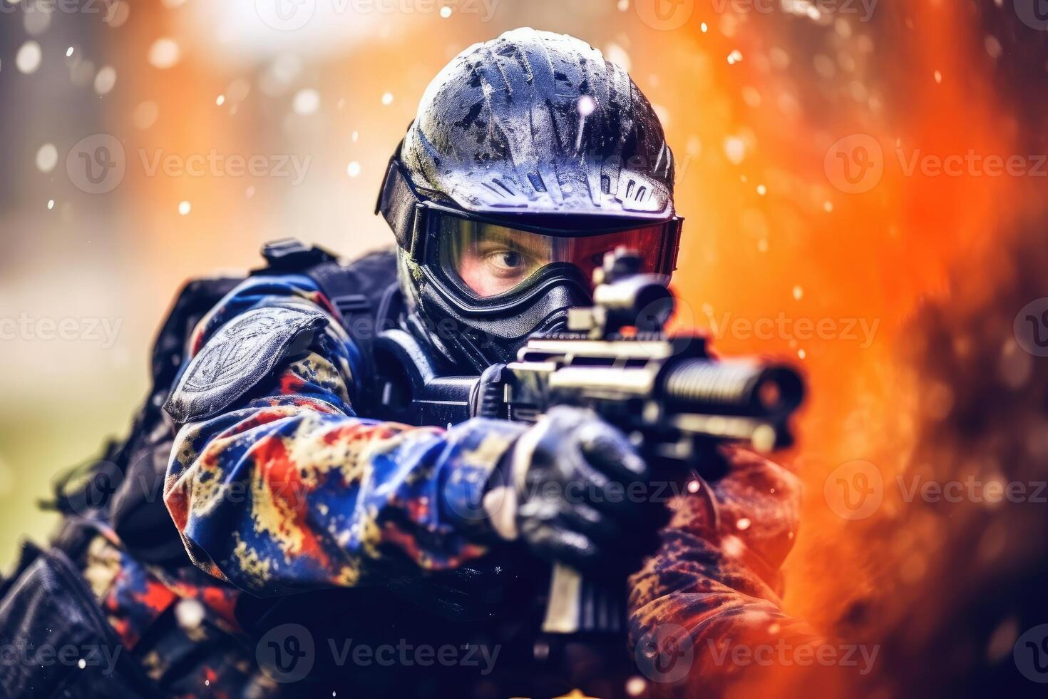 Close-up shot of a male paintball player pointing his paintball gun at the camera. photo