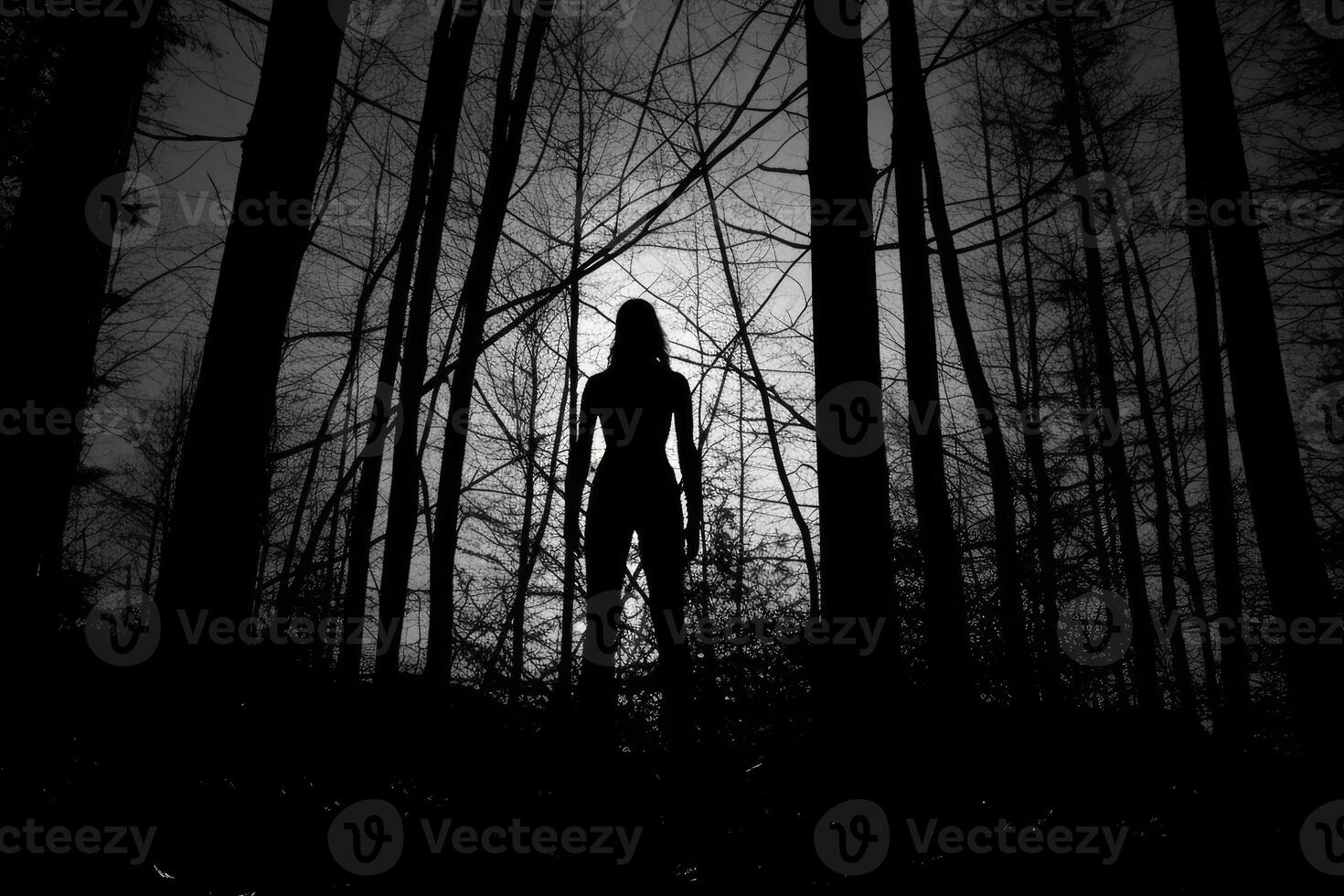 A witch standing alone in a forest clearing, silhouetted against a huge, glowing full moon. photo
