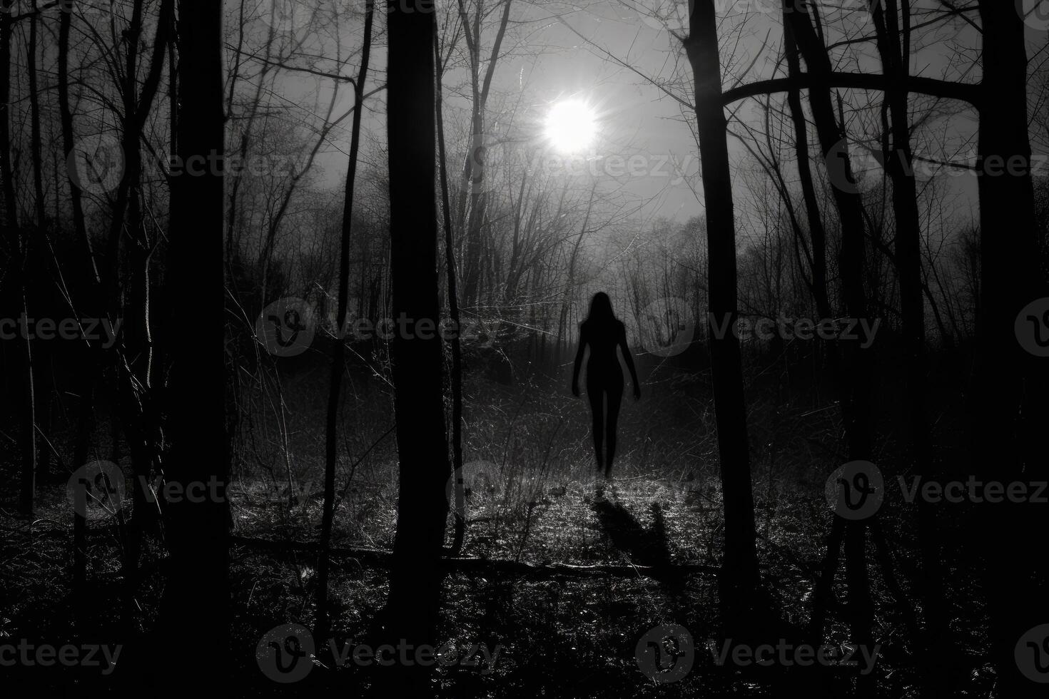 A witch standing alone in a forest clearing, silhouetted against a huge, glowing full moon. photo