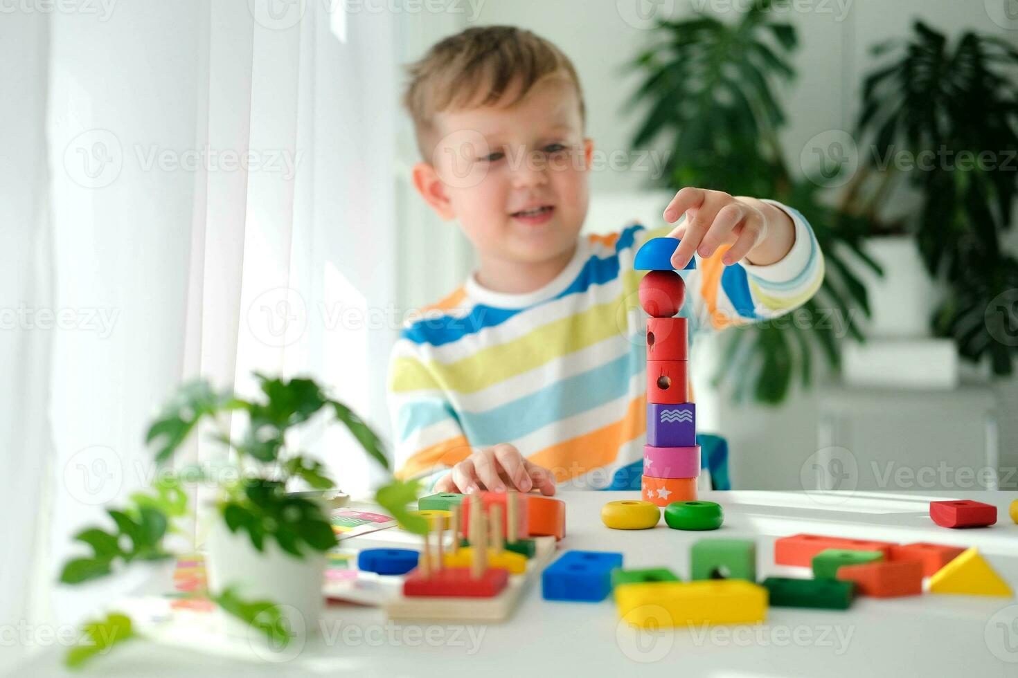 A little boy plays with wooden toys and builds a tower. Educational logic toys for children. Montessori games for child development. Children's wooden toy. photo