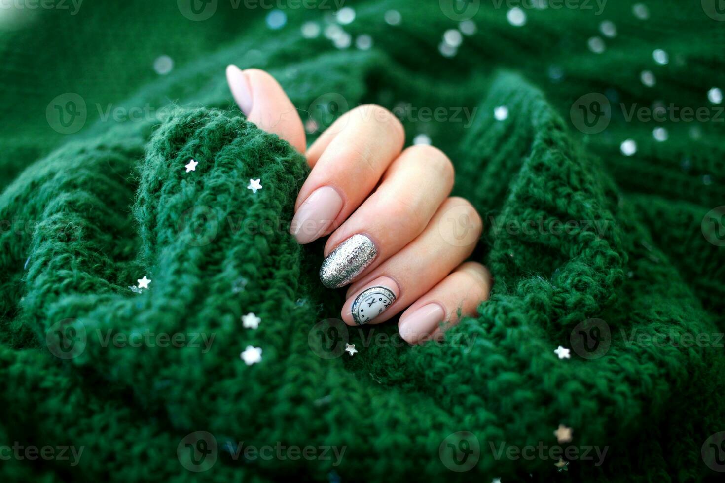 hermosa hembra mano en un verde suéter con Navidad uña diseño. uña diseño, manicura con campanas modelo. goma laca, gel polaco. foto