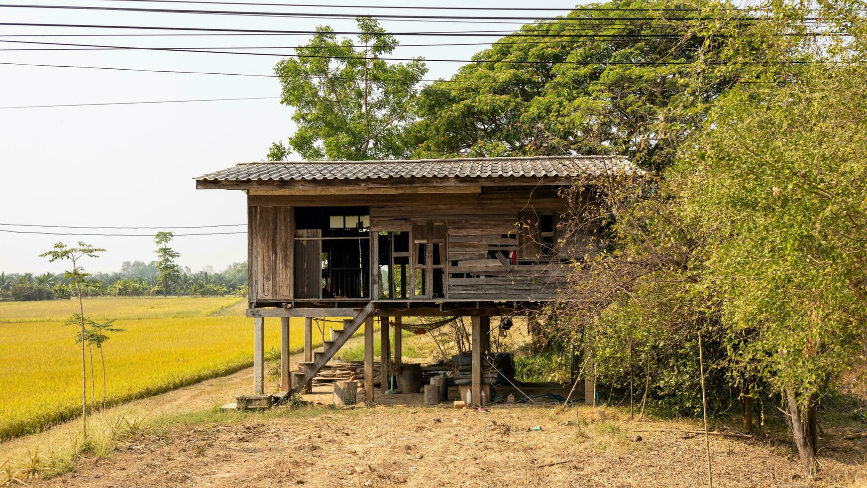 A view of an abandoned and decayed old wooden house mounted on the ground. photo