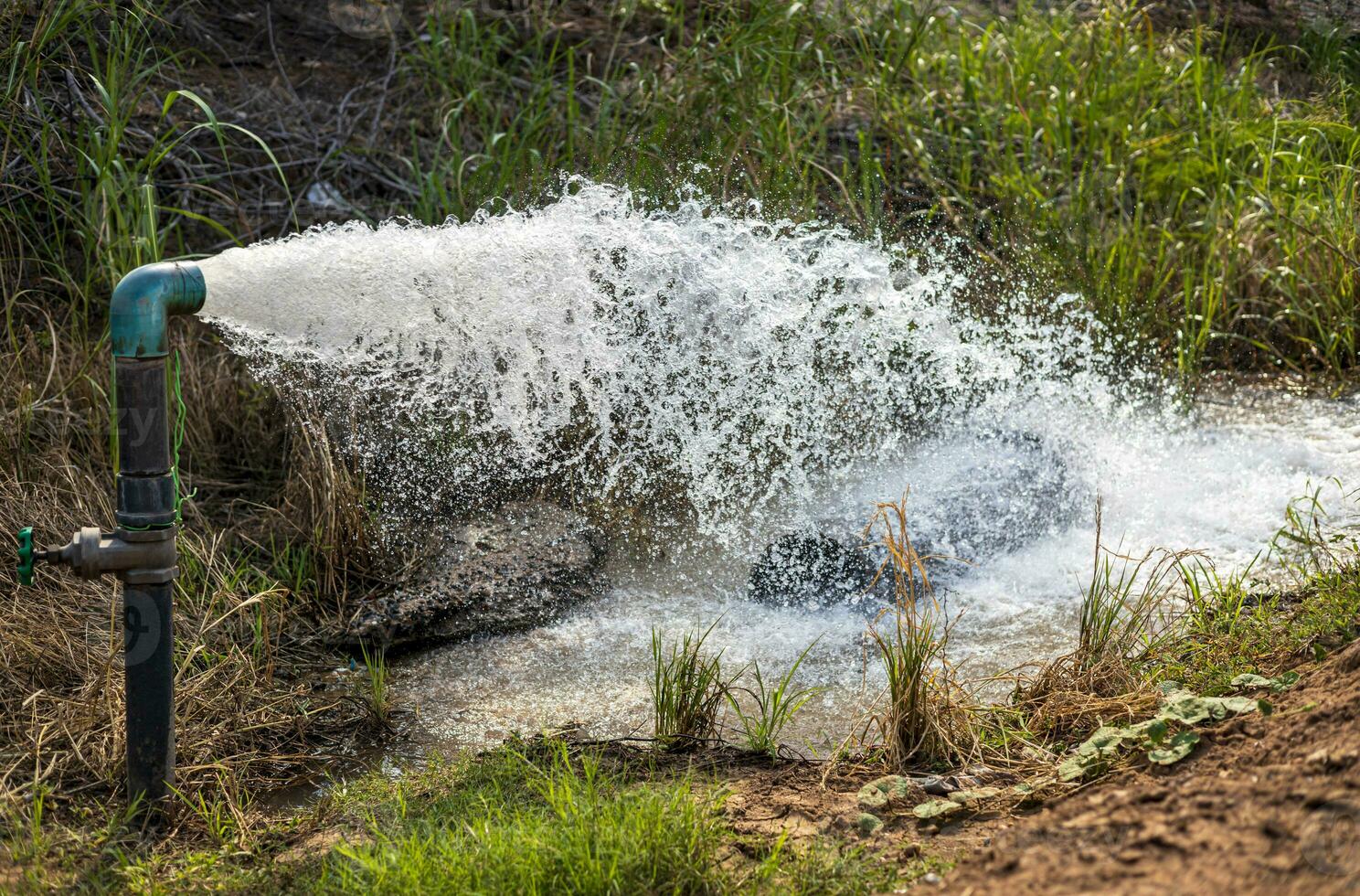 Close-up view of water gushing violently out of a water supply pipe. photo