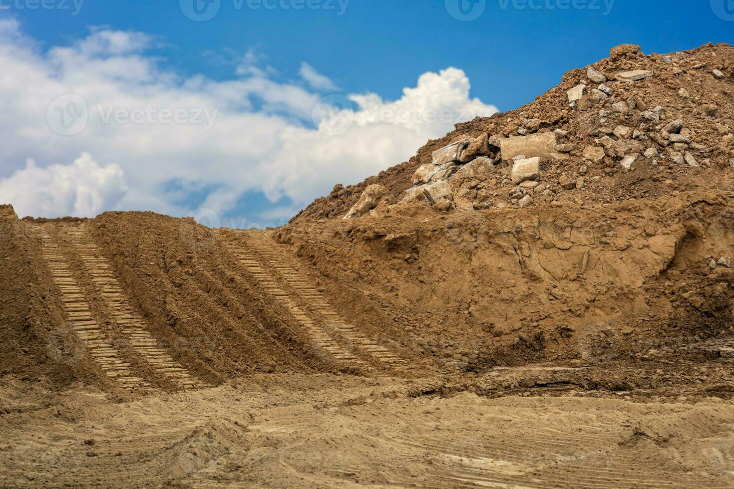 Mounds of sand and concrete debris that have been excavated are poured together with backhoe wheels. photo