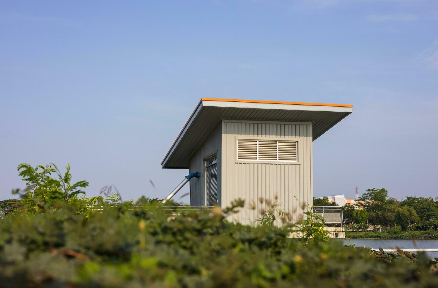 A low angle view through the grass to a blue zinc hut with water pipes. photo