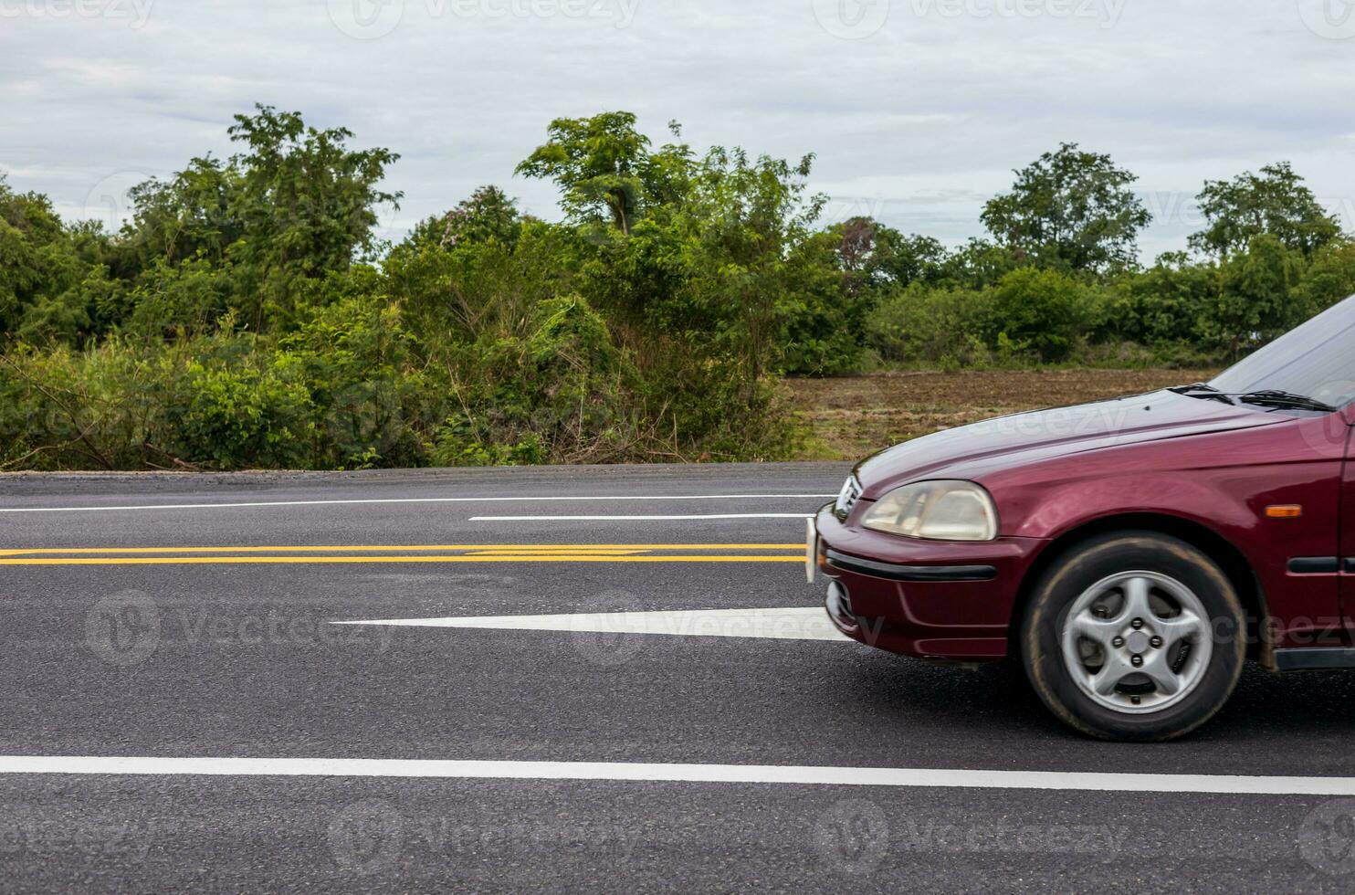 un de cerca ver de el lado de un nuevo pista la carretera con un rojo coche paso por. foto