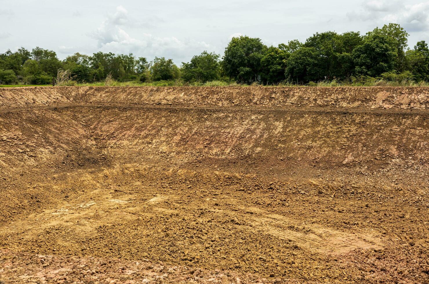 un antecedentes ver de el orilla, un montículo de suciedad excavado dentro un canal o un grande estanque. foto