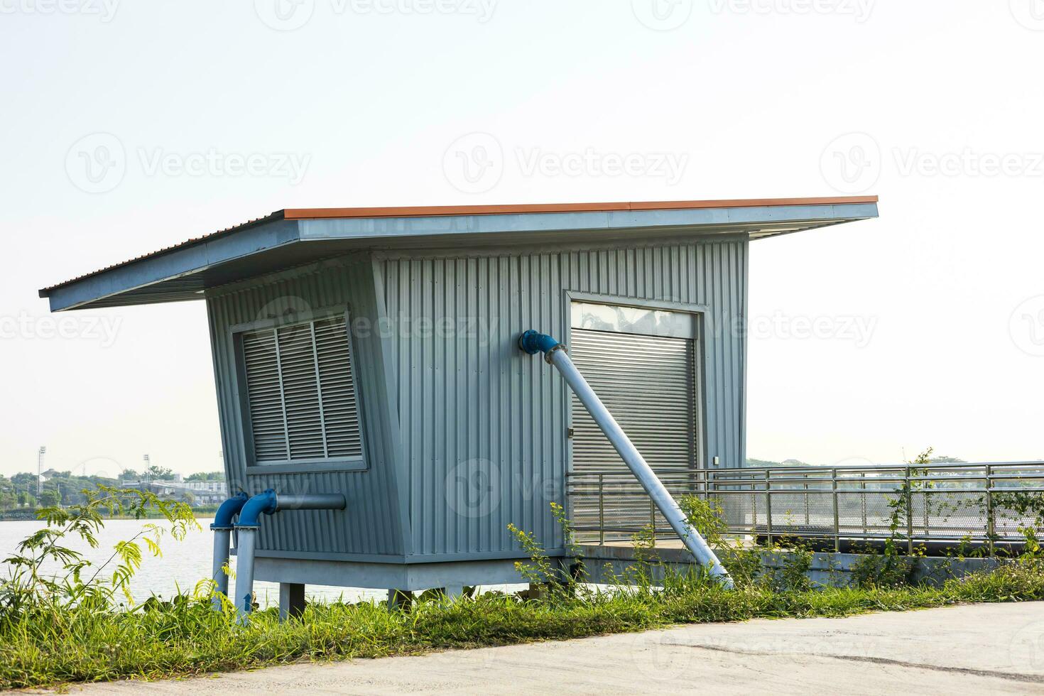 A low angle view through the grass to a blue zinc hut with water pipes. photo