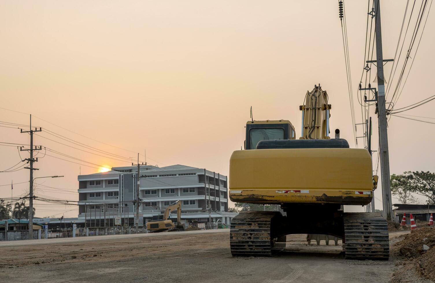 Rear view of an old yellow backhoe parked on a roadway being renovated. photo