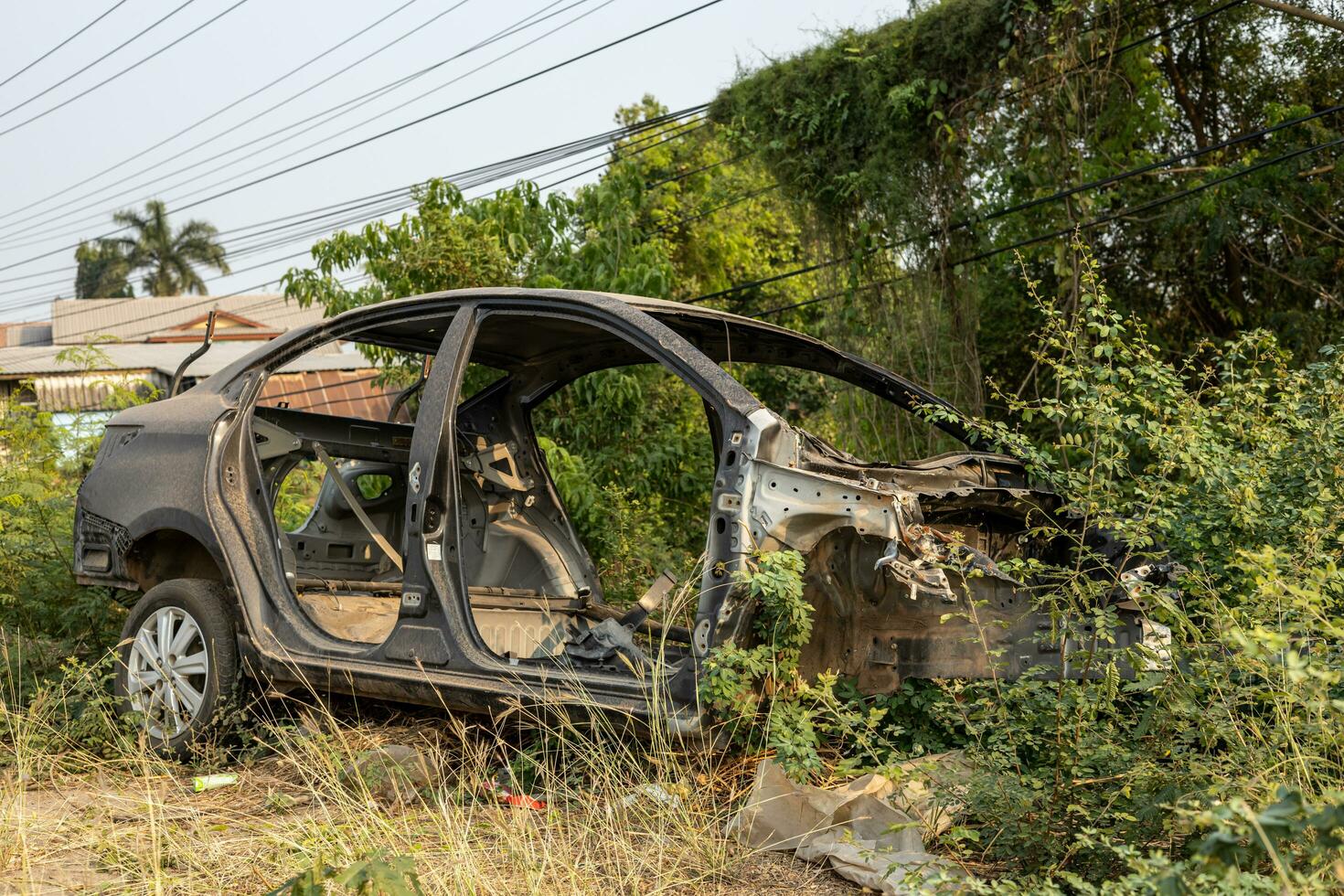 Side view of a black car wreck dismantled to its steel frame. photo