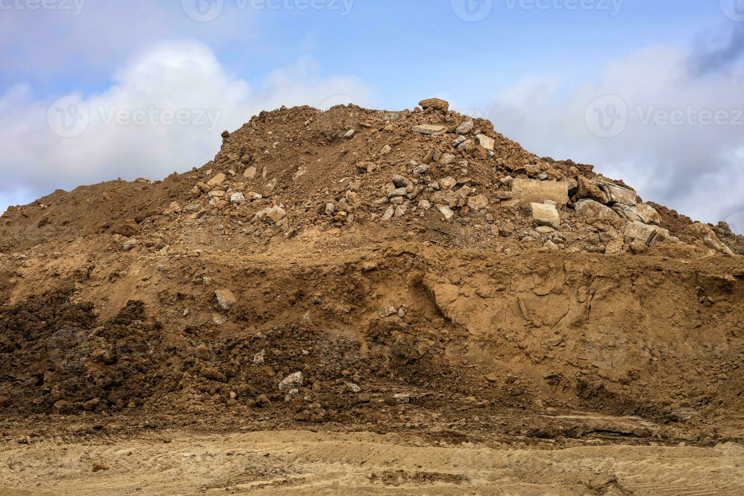 excavado montículos de arena y hormigón escombros son apilado juntos en contra rueda rastros foto