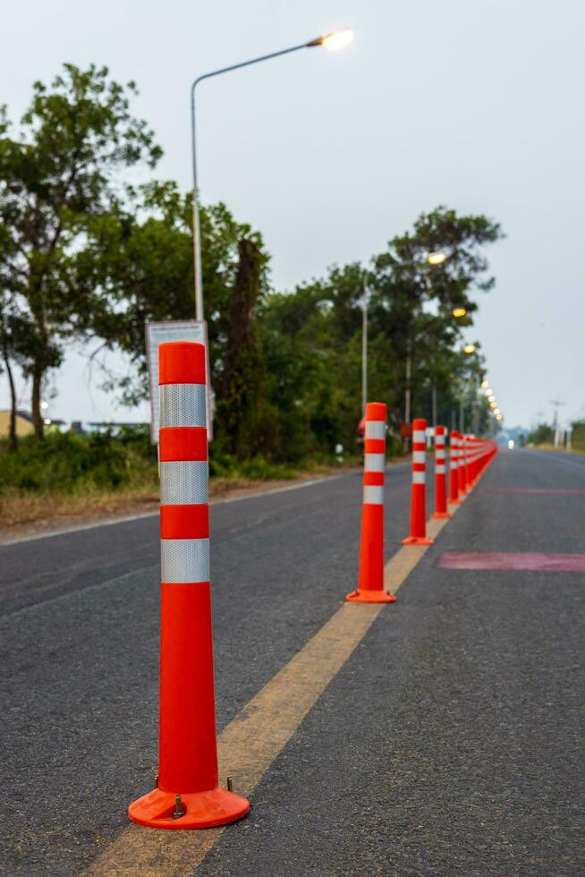 A low-angle view of many reflective orange plastic poles set up as a sign to prevent oncoming traffic. photo