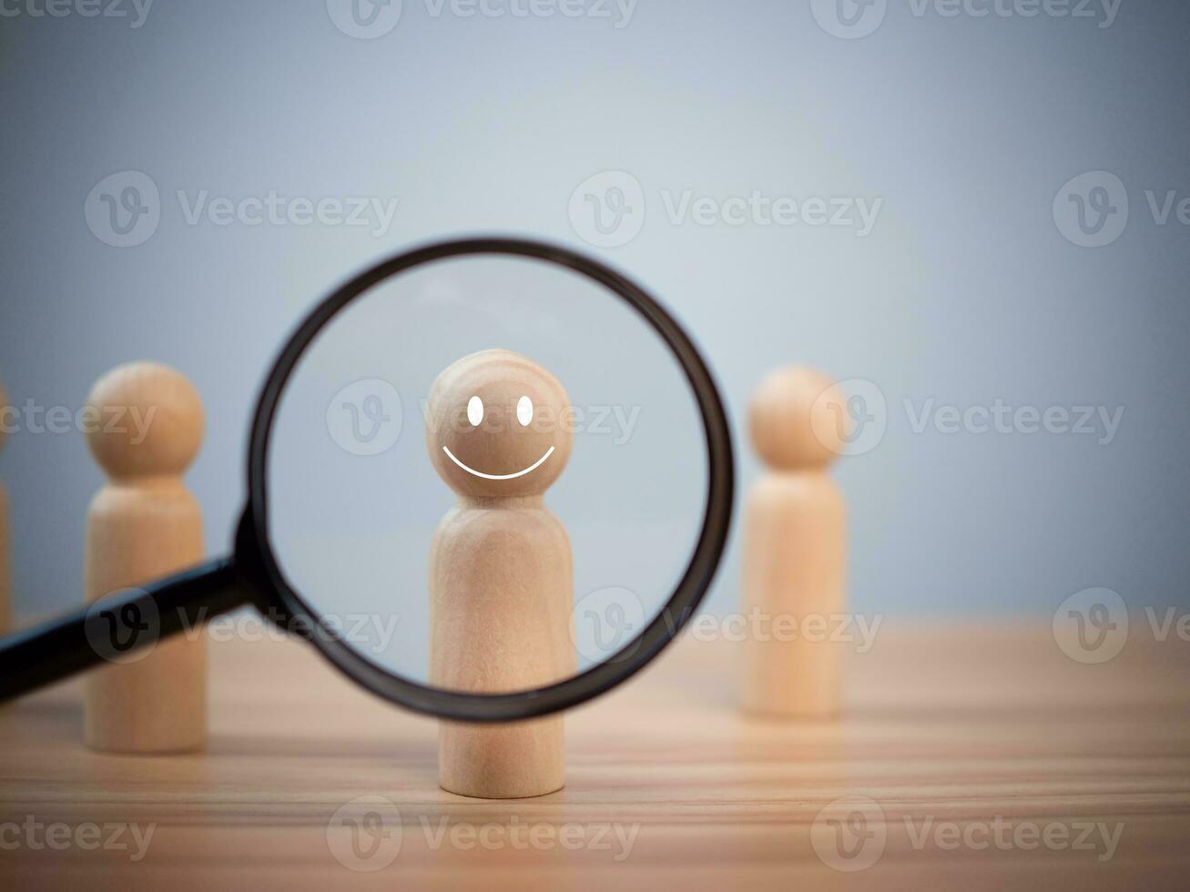 The wooden doll smiled through the magnifying glass inside. Represents customer satisfaction and happiness surveys. Great Customer Assessment Concept photo
