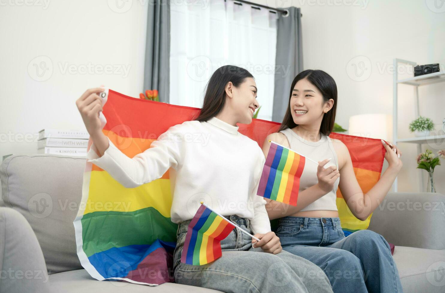 Happy lesbians hugging each other, laughing, whispering in ear having fun standing at home. Two lovely cute women with various styles hugging each other. relationship concep photo