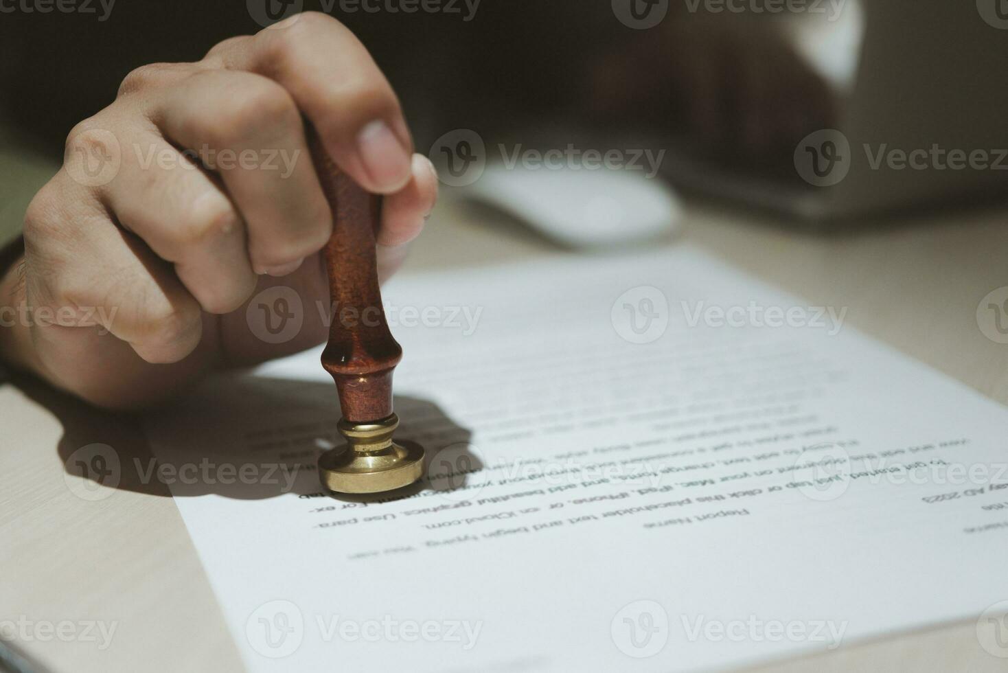 Hand holding rubber stamp on document paper.Approval job application. Legal Contract Work Paper and public notary clerk certificate and agreements on desk. photo