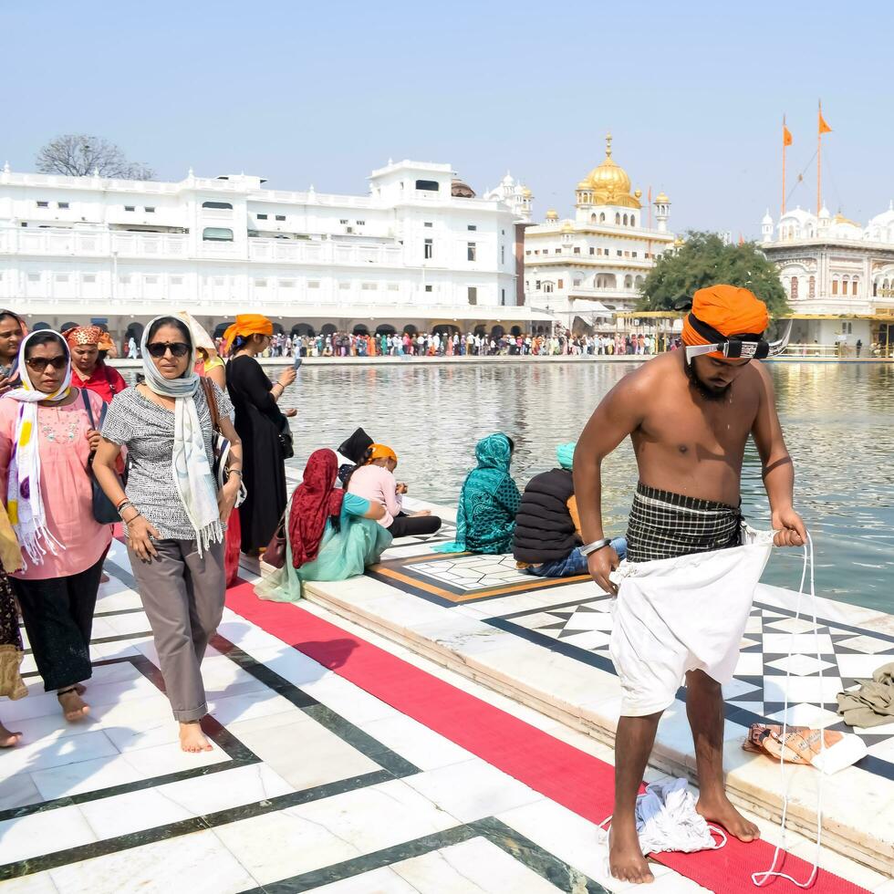 Amritsar, India - May 31 2023 - Unidentified devotees taking holy dip in sarovar at Golden Temple - Harmandir Sahib in Amritsar, Punjab, India, Famous indian sikh landmark, Golden Temple photo