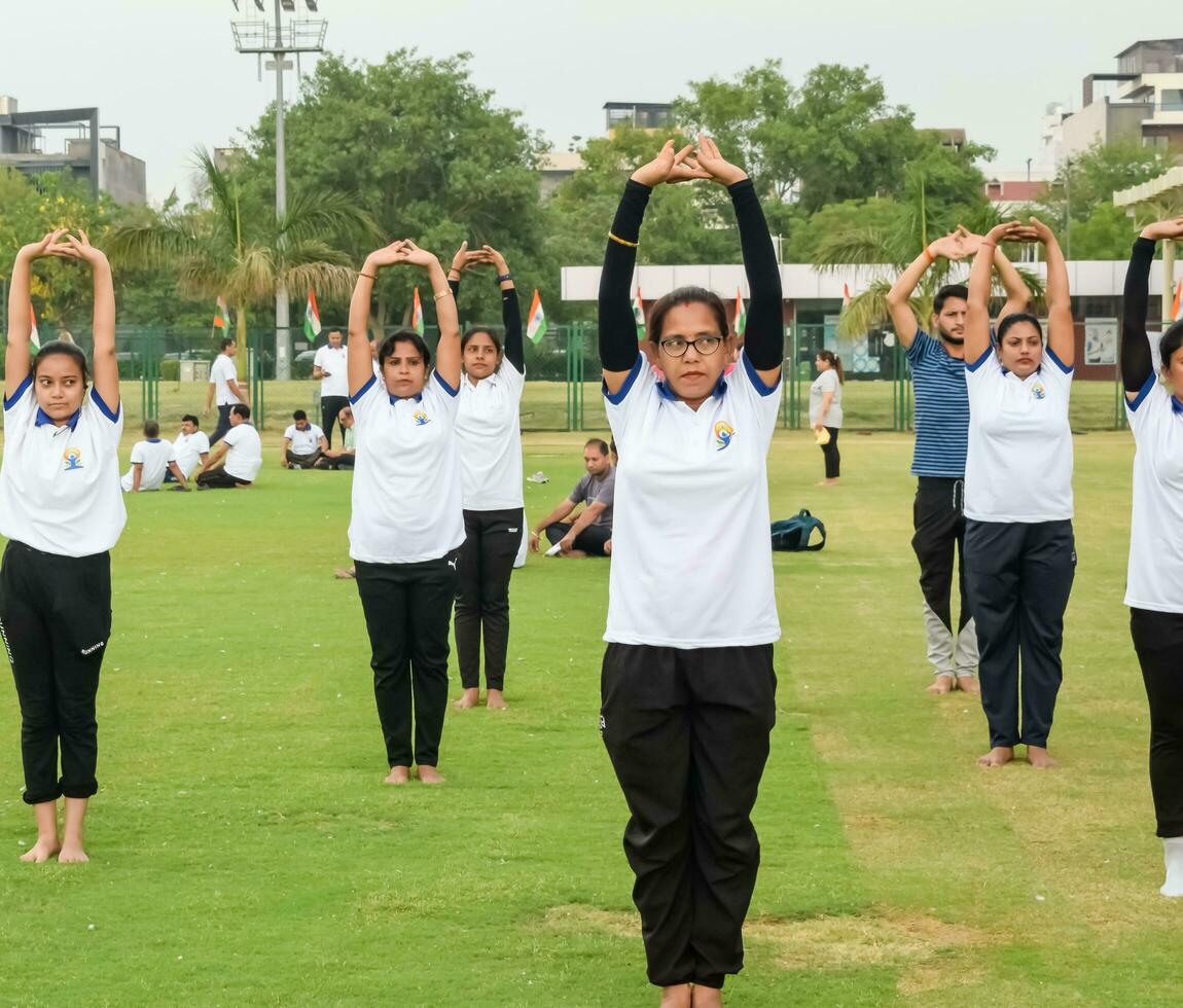 nuevo Delhi, India, junio 21, 2023 - grupo yoga ejercicio sesión para personas a yamuna Deportes complejo en Delhi en internacional yoga día, grande grupo de adultos asistiendo yoga clase en Grillo estadio foto