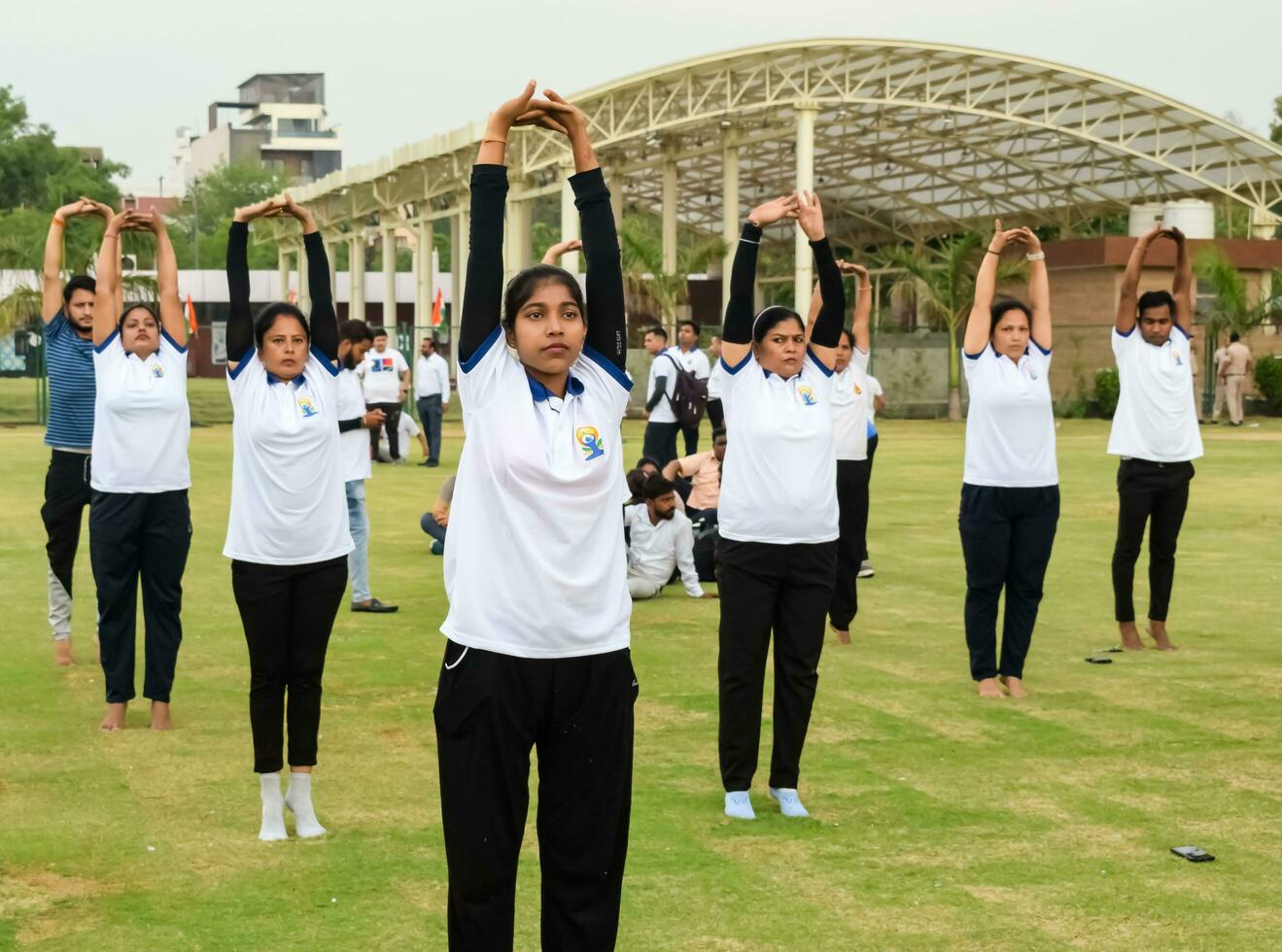 New Delhi, India, June 21, 2023 - Group Yoga exercise session for people at Yamuna Sports Complex in Delhi on International Yoga Day, Big group of adults attending yoga class in cricket stadium photo