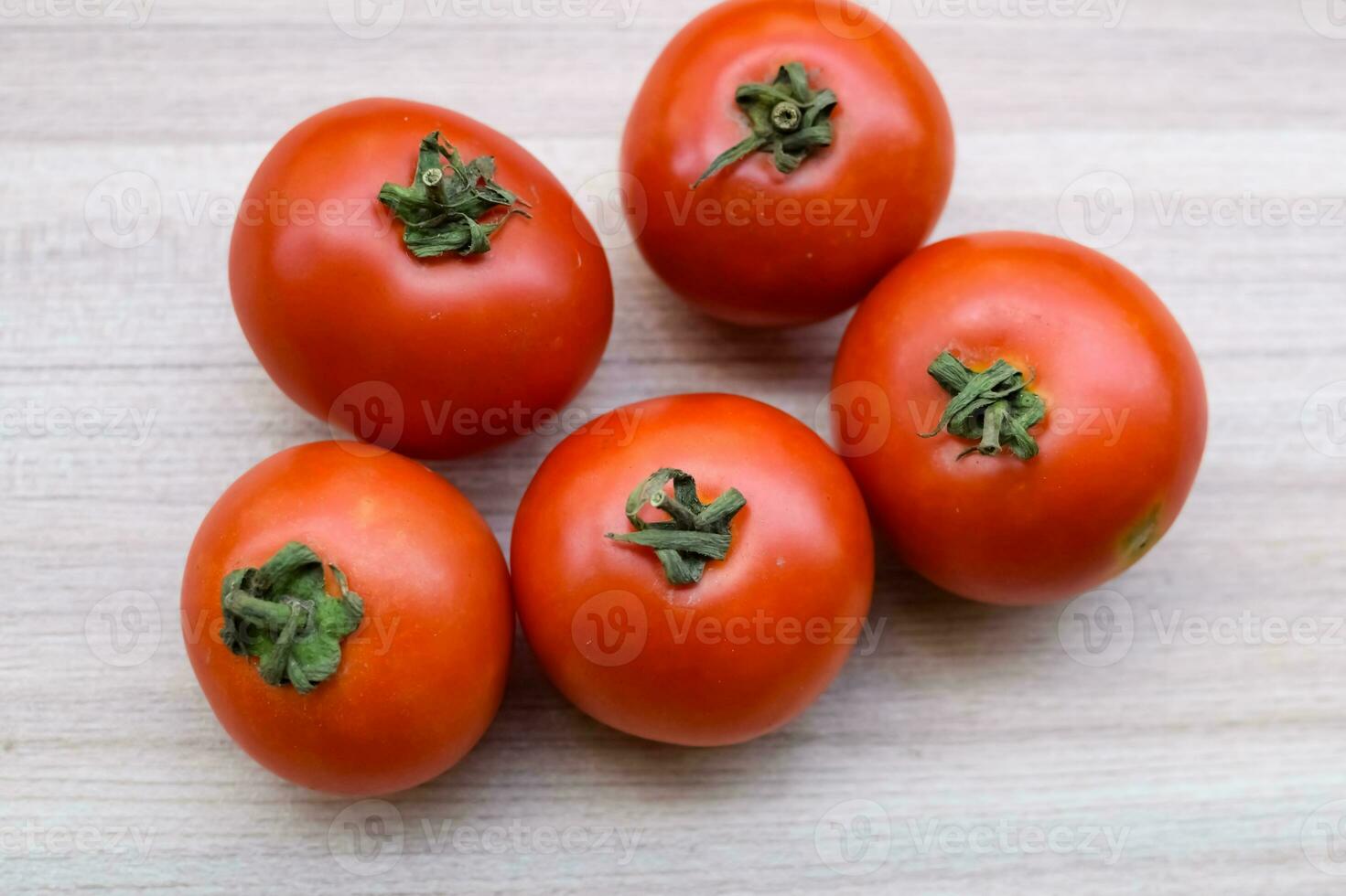 Red tomato on plain wooden table, essential vegetables for all essential foods, view of unpeeled vegetables with plain background photo