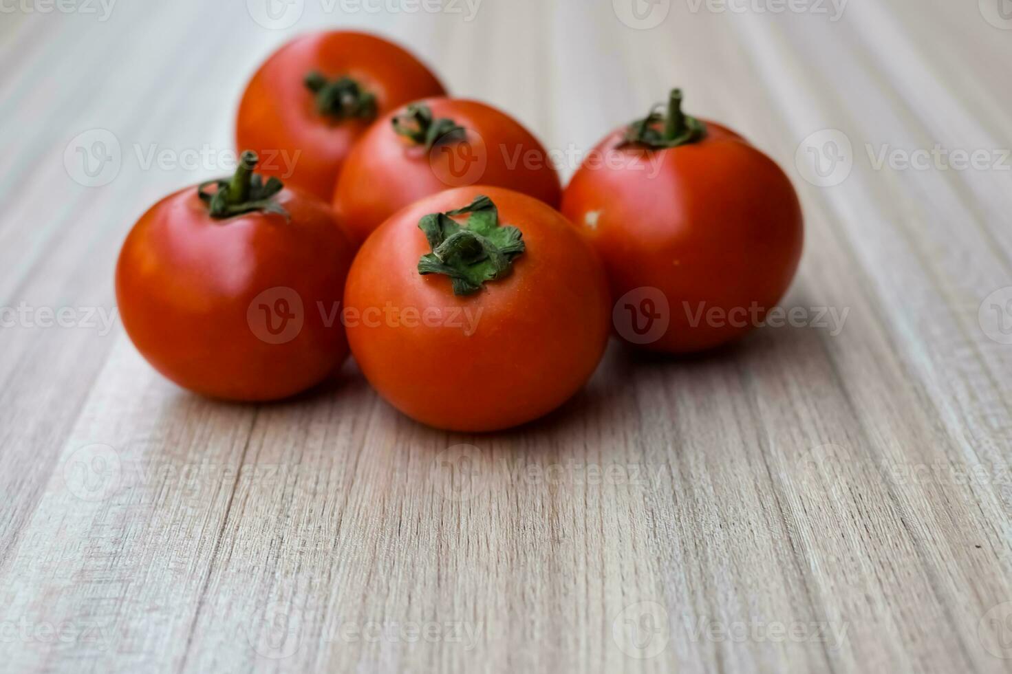 Red tomato on plain wooden table, essential vegetables for all essential foods, view of unpeeled vegetables with plain background photo