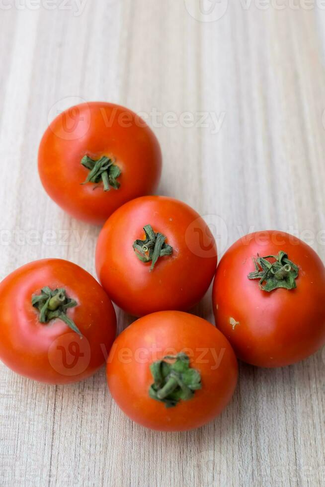 Red tomato on plain wooden table, essential vegetables for all essential foods, view of unpeeled vegetables with plain background photo