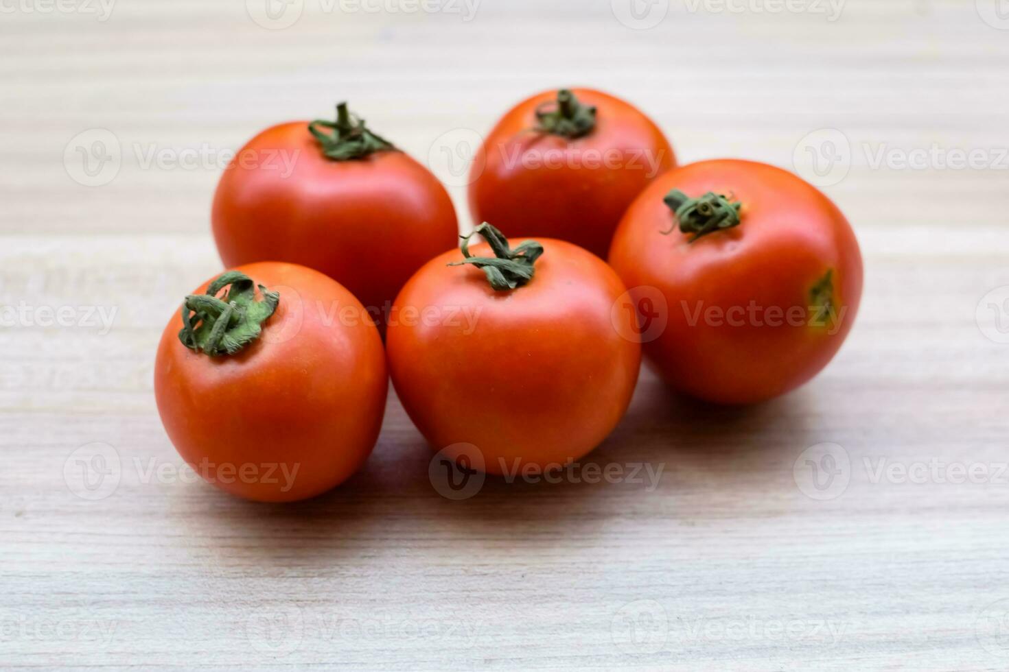Red tomato on plain wooden table, essential vegetables for all essential foods, view of unpeeled vegetables with plain background photo