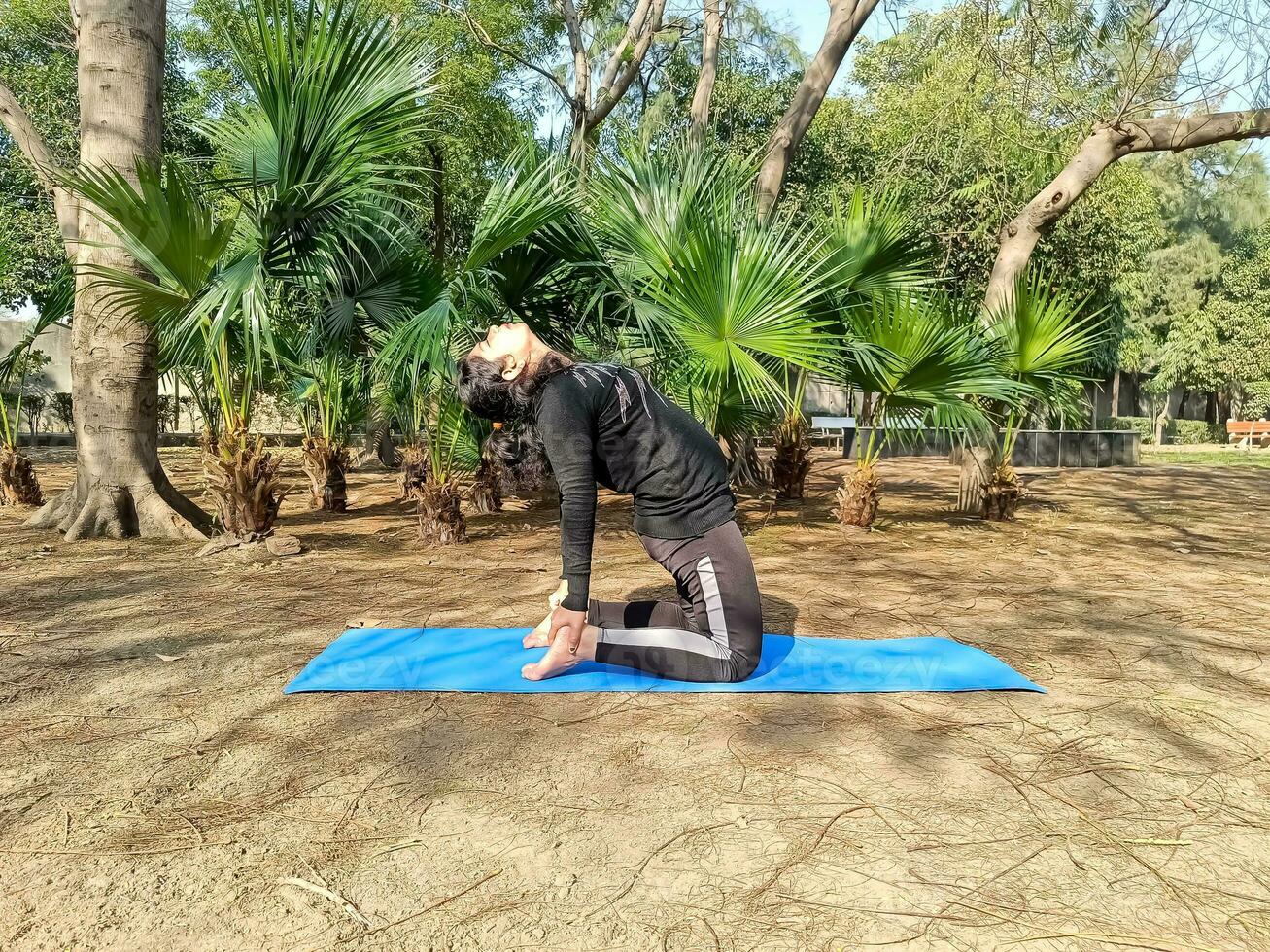 Young Indian woman practicing yoga outdoor in a park. Beautiful girl practice basic yoga pose. Calmness and relax, female happiness. Basic Yoga poses outdoor photo