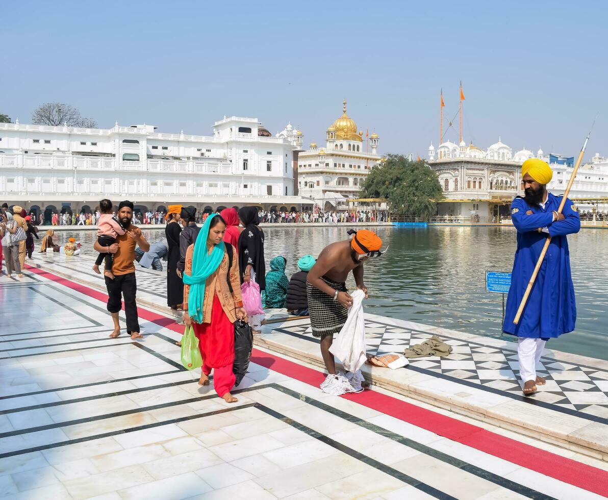 Amritsar, India - May 31 2023 - Unidentified devotees taking holy dip in sarovar at Golden Temple - Harmandir Sahib in Amritsar, Punjab, India, Famous indian sikh landmark, Golden Temple photo
