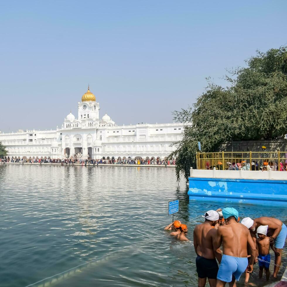 Amritsar, India - May 31 2023 - Unidentified devotees taking holy dip in sarovar at Golden Temple - Harmandir Sahib in Amritsar, Punjab, India, Famous indian sikh landmark, Golden Temple photo