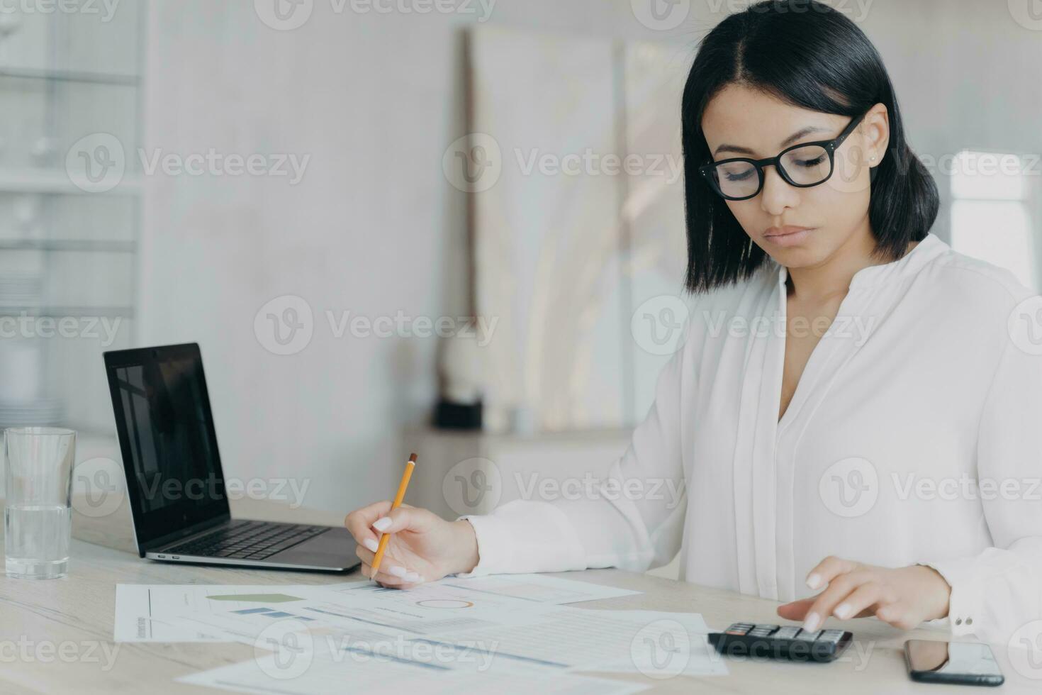 Remote accountant is calculating profit. Young hispanic bookkeeper is working distantly from home. photo