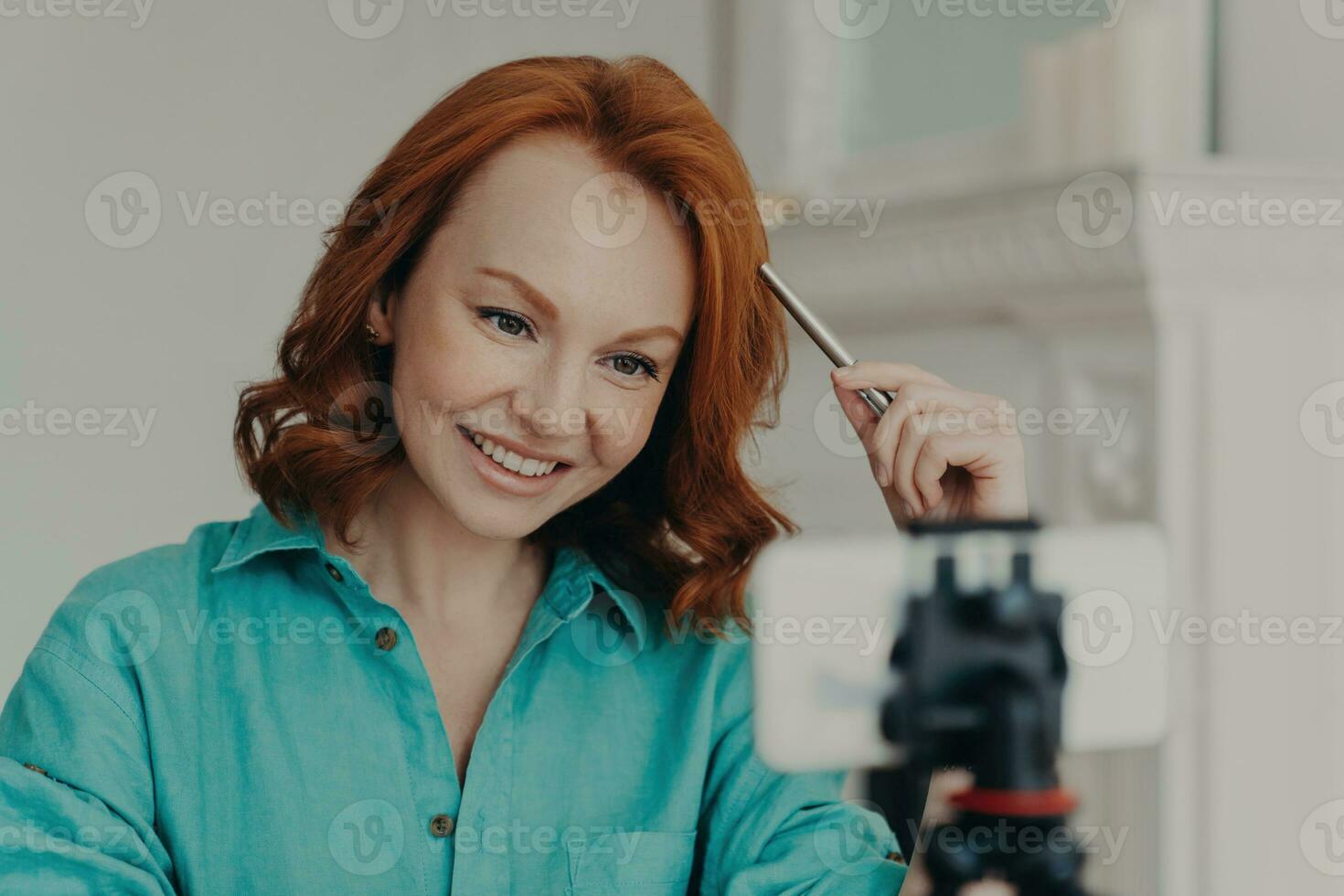 Happy redhead vlogger records webcam videos, gives advice, teaches languages as online teacher. Engaging with subscribers, webinars too. photo
